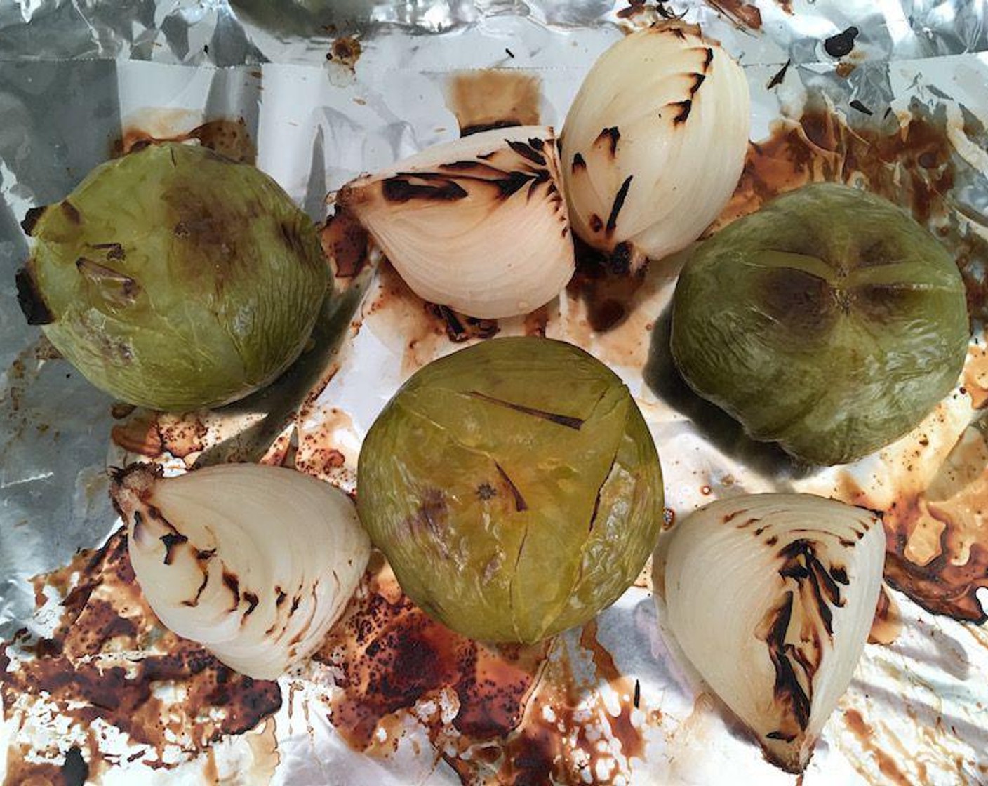 step 2 Place whole Green Tomatoes (3) and onion quarters on a baking sheet lined with aluminum foil. Roast under broiler, flipping the vegetables halfway through, until they are charred on both sides. Allow to cool for a few minutes before handling.