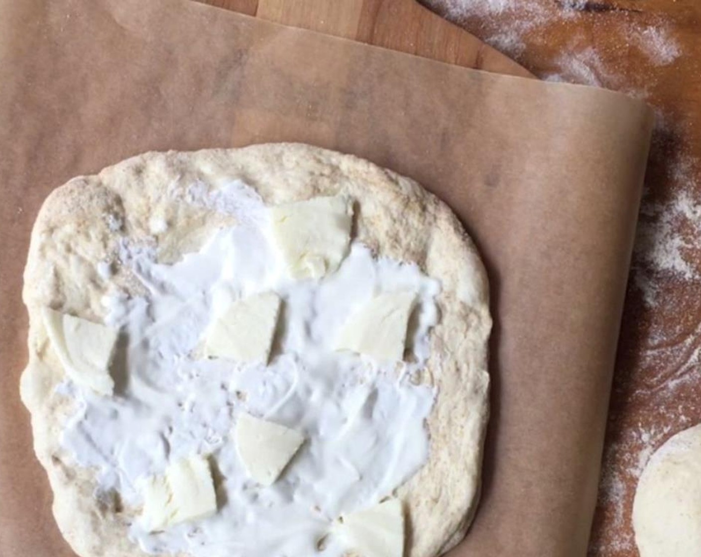 step 7 When you are ready to bake, gently stretch one round into a 10 to 11 inch circle. Transfer to a parchment paper-lined pizza peel. Spread a few tablespoons of Crème Fraîche (to taste) over the surface of the dough. Scatter Fresh Mozzarella Cheese Ball (to taste) over top.