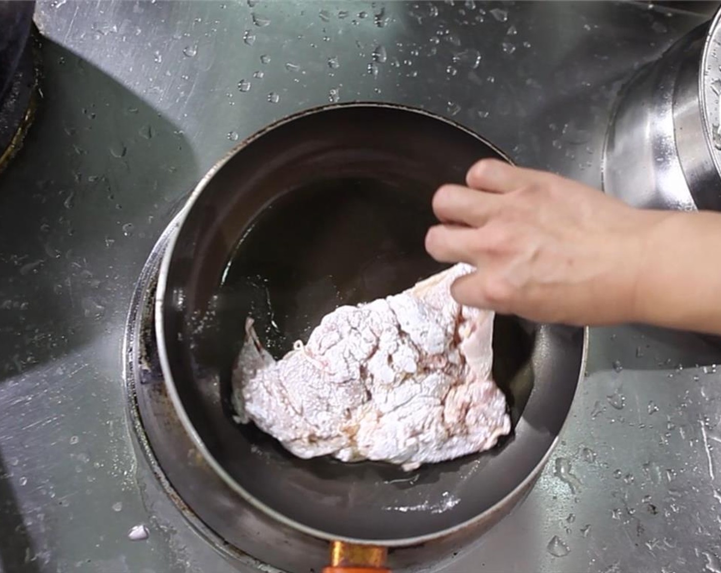 step 4 When it is hot enough to fry, lay the dredged chicken thighs into the oil away from you.