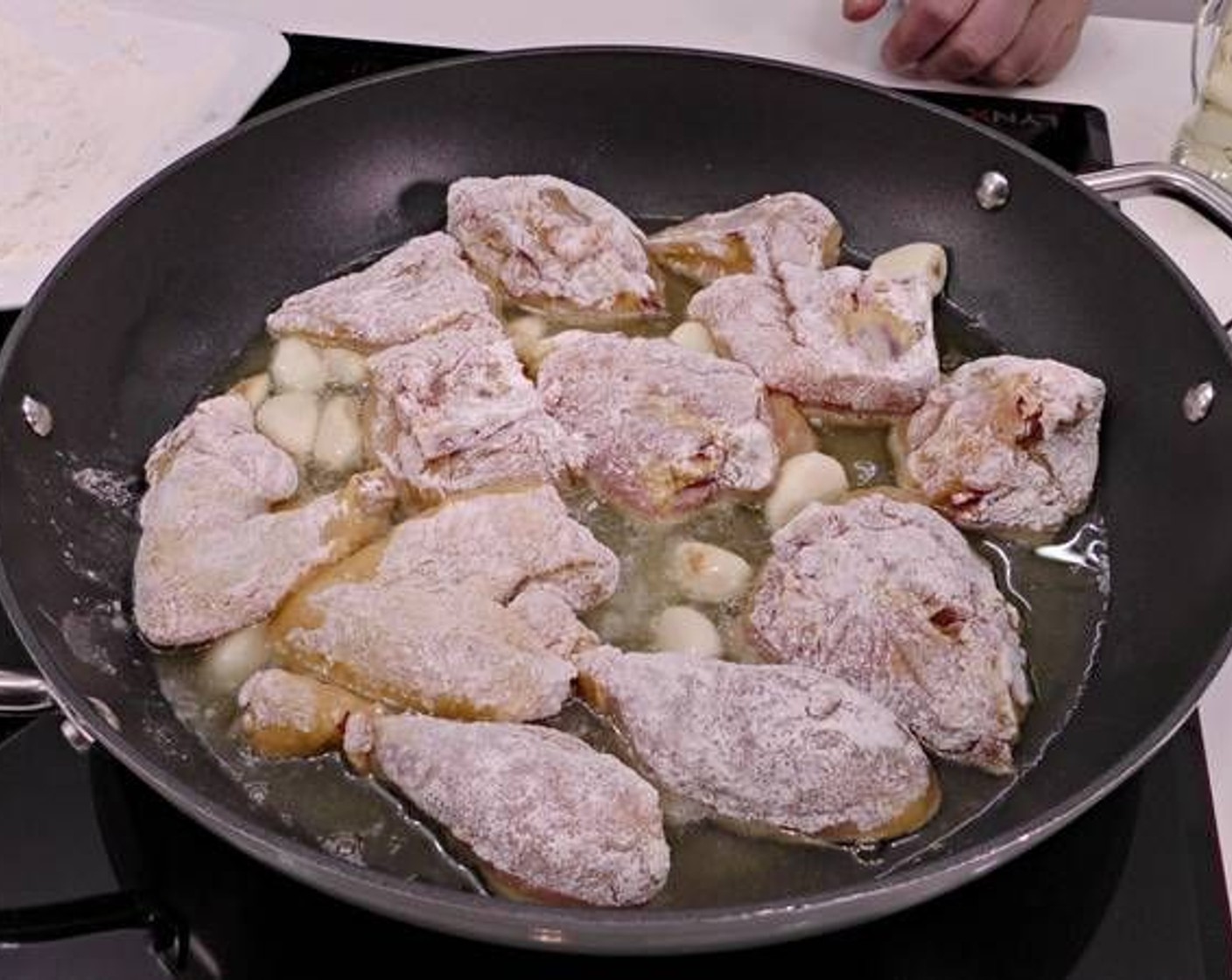 step 3 Next, coat the chicken pieces in All-Purpose Flour (to taste) and place them in the pan alongside the garlic.
