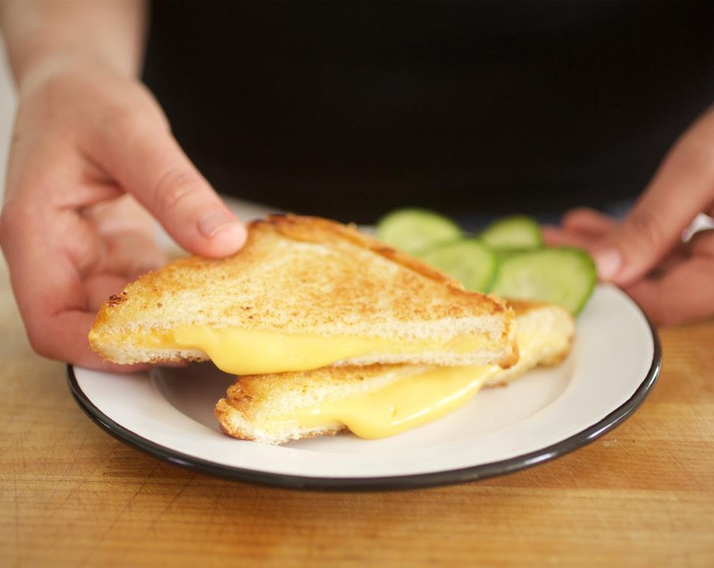 step 8 On two plates, plate the grilled cheese in the middle and place pickled cucumbers on the side. Serve and enjoy!