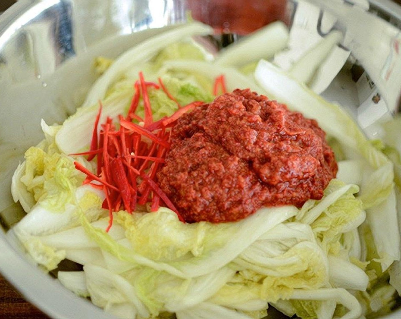 step 12 Place drained cabbage leaves in a large shallow mixing bowl. Add the Red Chili Peppers (2) and Leek (1) if using, and the kimchi filling.