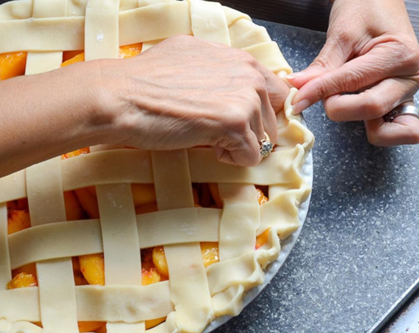 step 10 Any excess or hanging dough should be tucked under on itself. Press your thumb and forefinger together and gently place it on the rim of the dough. Use the knuckle on your other hand to crimp the dough. Continue around the circumference of the pie.