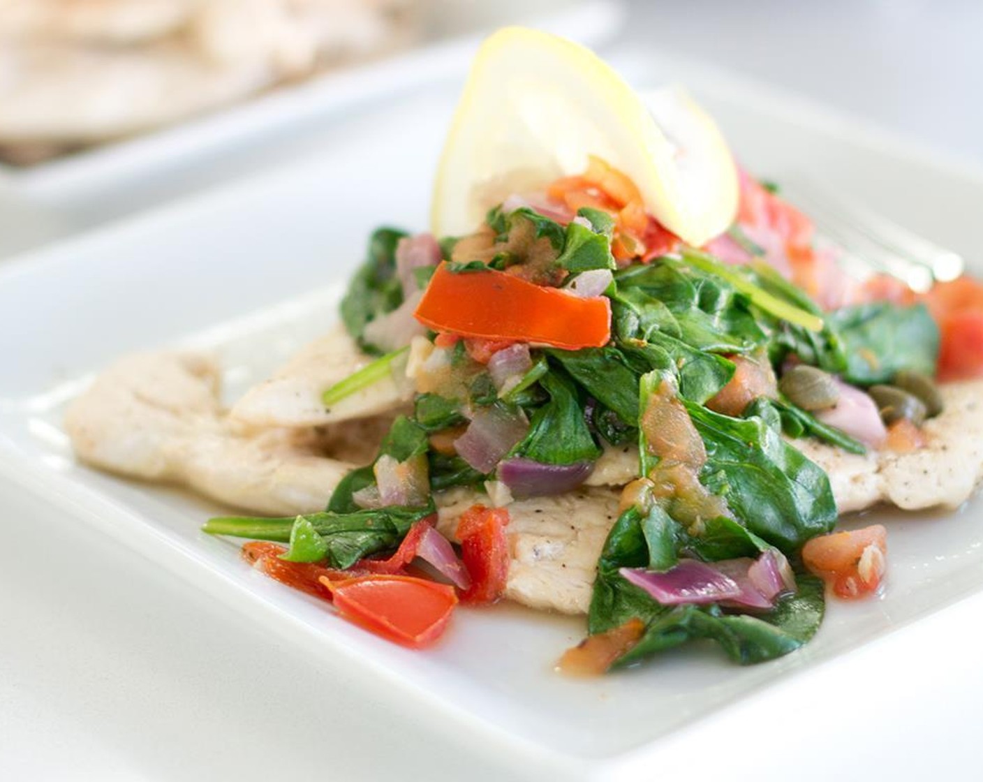 step 10 To serve, plate chicken, top with the tomato/spinach medley, and garnish with a wedge of lemon.