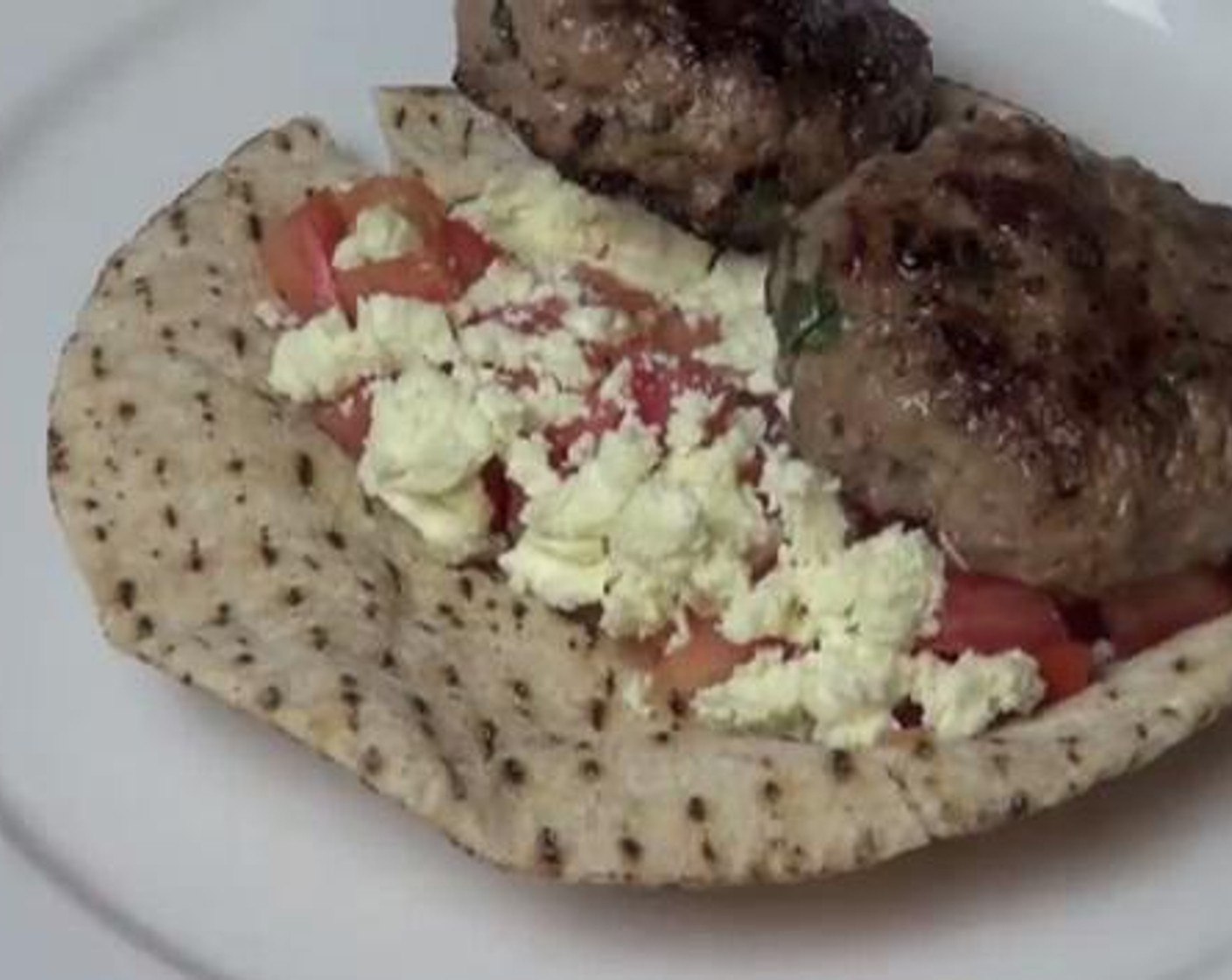 step 4 Add the diced Tomatoes (2), and Feta Cheese (2/3 cup) to your Pita Bread (1). Place two of your patties on top, and you are good to serve.