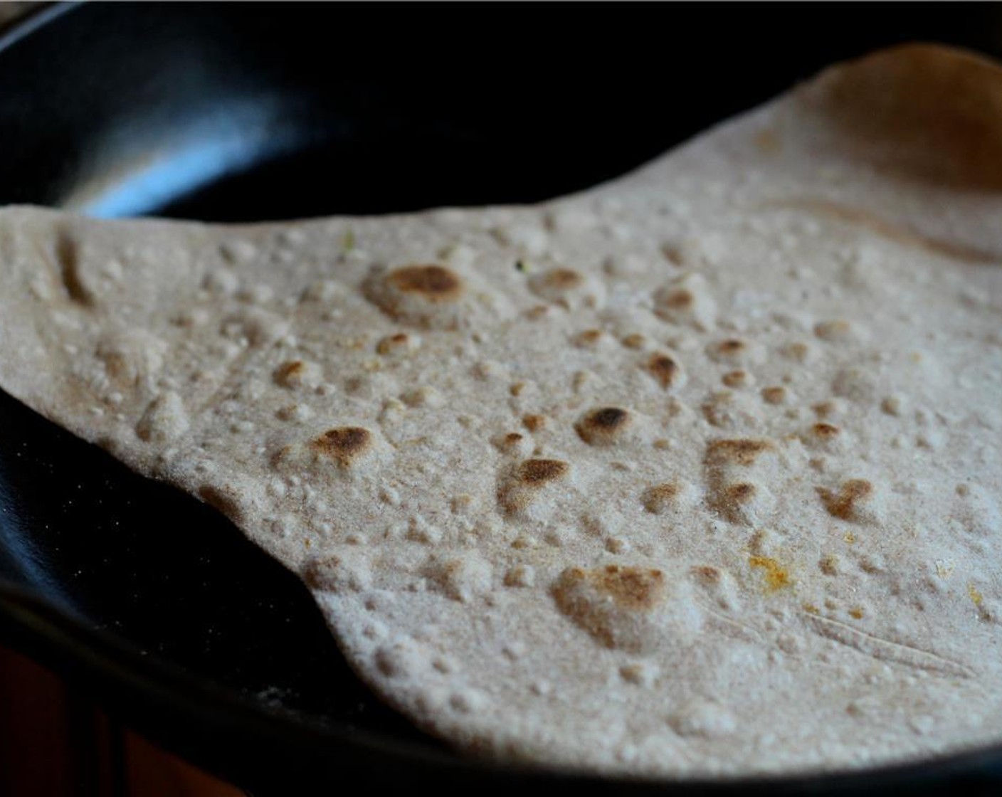 step 11 Place a non-stick skillet on medium heat. Once the pan is hot, add the roti and cook until the dough lifts away from the pan around the edges and small bubbles form. Flip the bread over and cook the other side.