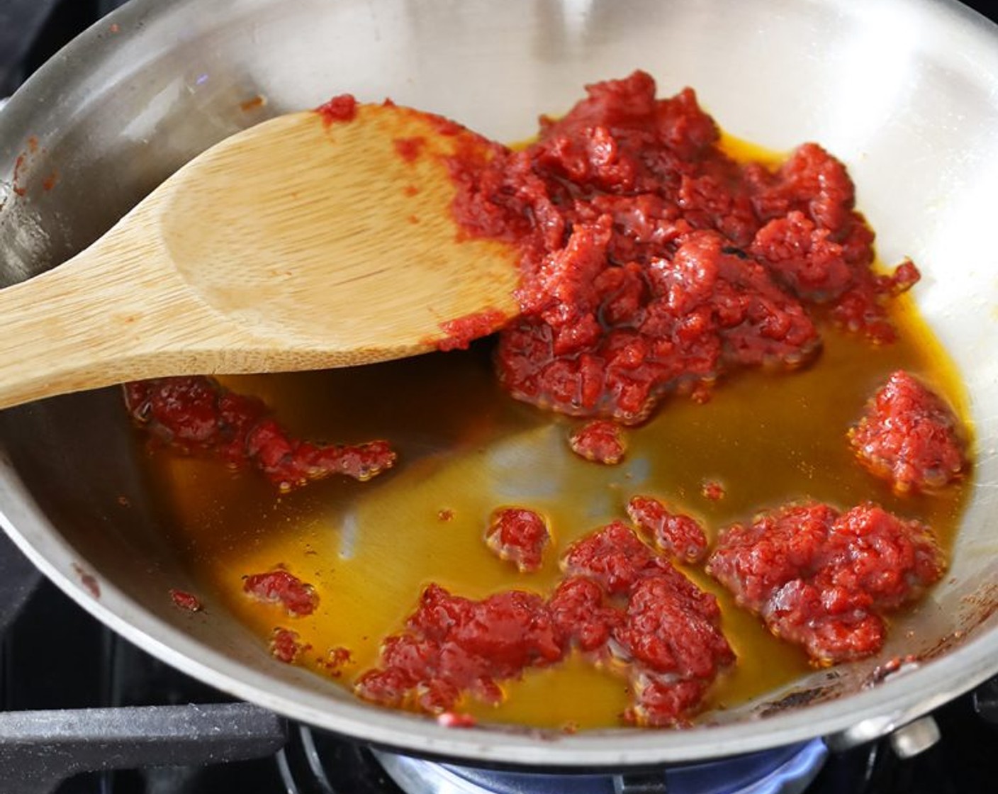 step 2 Cook, breaking up the tomato paste with a wooden spoon and scraping the bottom of the skillet until the oil is bright orange and the tomato paste has darkened in color, 2-3 minutes. Set aside to cool slightly.