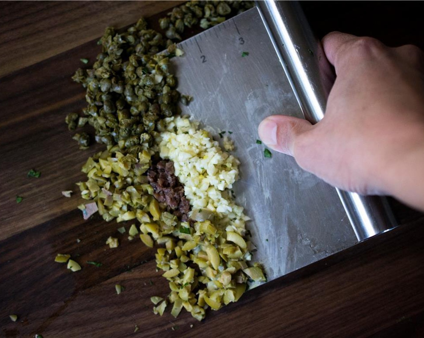 step 2 Add in Anchovy Fillets (3), Capers (1 Tbsp), Green Olives (3), Garlic (4 cloves) into the bowl of greens.