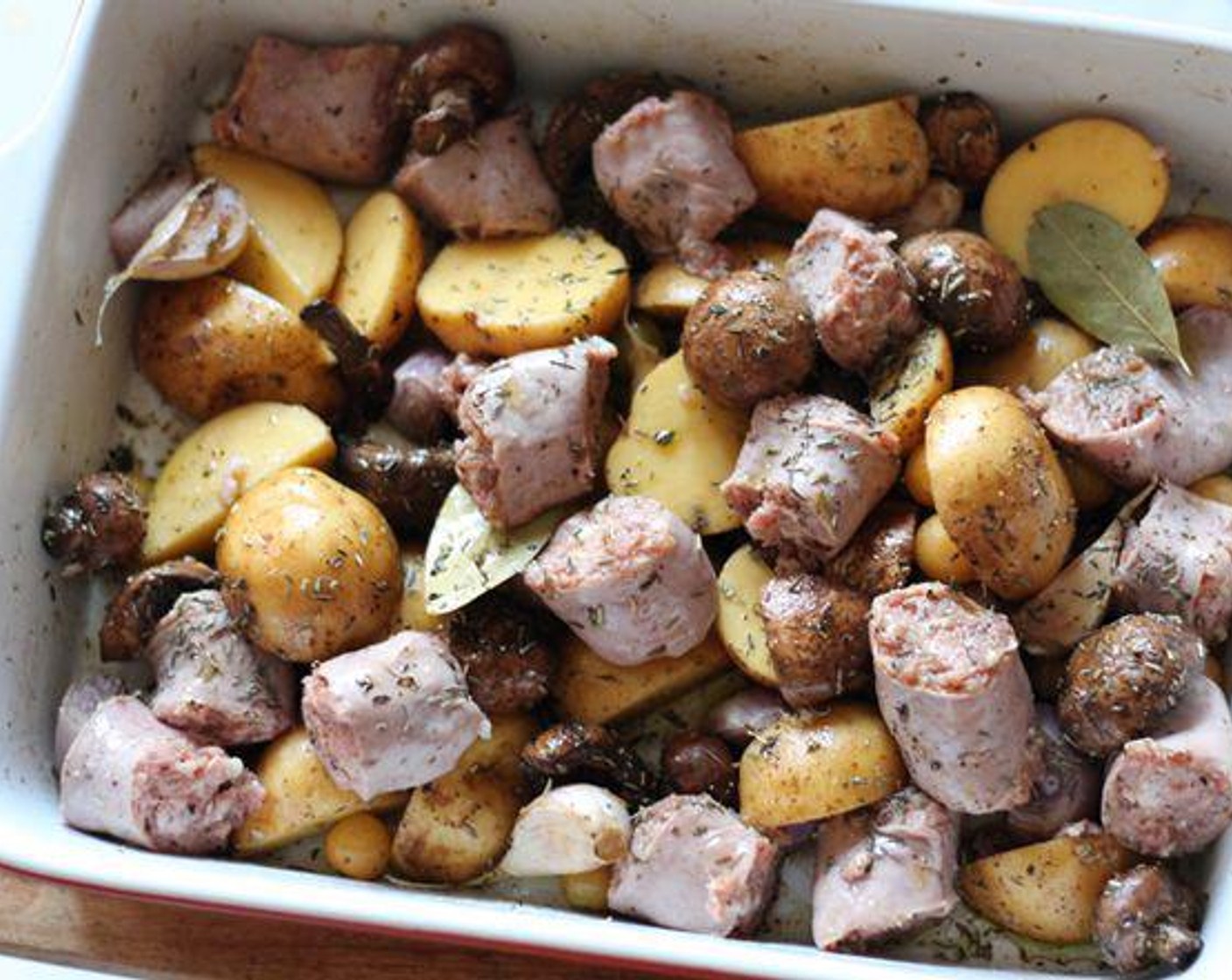 step 2 Mix Spicy Italian Sausage Link (1 lb), Yukon Gold Potatoes (6), Cremini Mushroom (1 cup), Tomatillo (1 cup), {@10:}, Shallots (2), Olive Oil (1/4 cup), Bay Leaves (2), Dried Thyme (1 Tbsp), Dried Rosemary (1 Tbsp), and Balsamic Vinegar (1 Tbsp) together in a baking pan coating everything evenly.