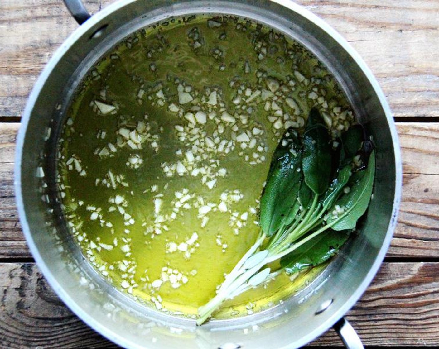step 1 Place the Olive Oil (4 Tbsp), Garlic (3 cloves), and Fresh Sage (1 bunch) in a soup pot and turn the heat to medium. Cook the garlic, stirring it until it becomes colored a very pale gold.