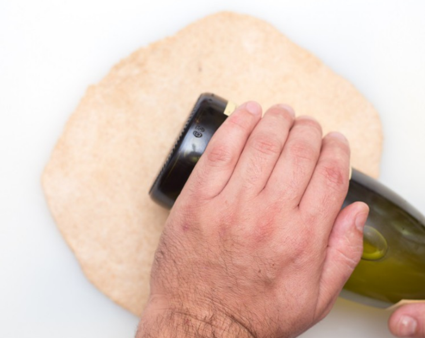 step 9 Using a rolling pin or straight-sided bottle, such as a wine bottle, roll each piece into a circle 8-10 inches in diameter. Place on 1 end of prepared baking pan, and repeat with second dough.