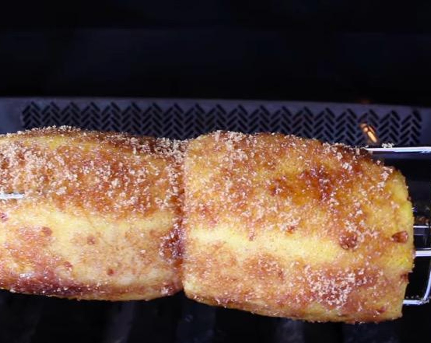 step 6 Apply the sugar mixture to the outside of each pineapple and place the rotisserie rod into the motor on the grill.