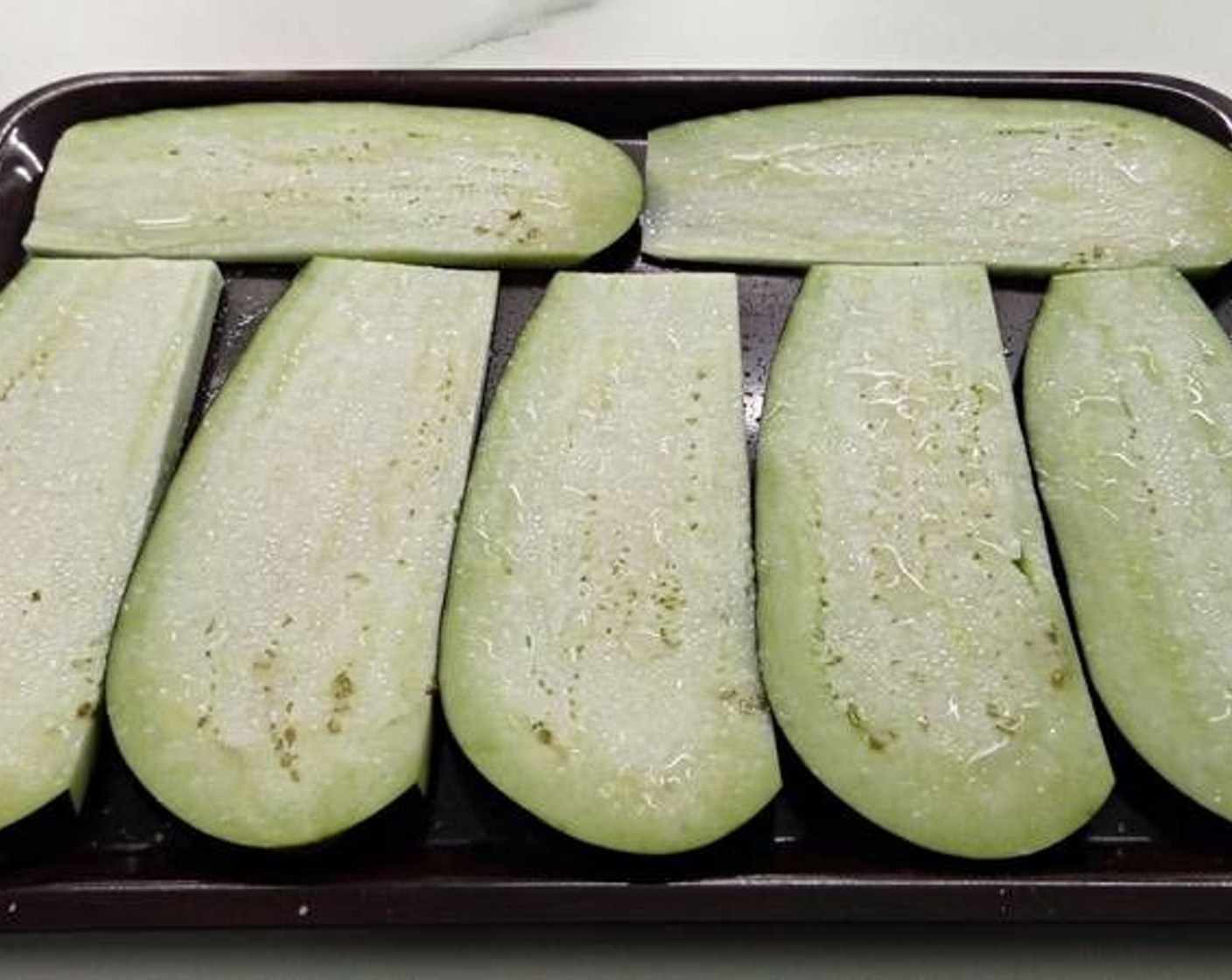 step 2 On a baking tray, lay out the eggplant slices and season with Salt (to taste). Let them sit for around 20 minutes so the salt can draw out the moisture.