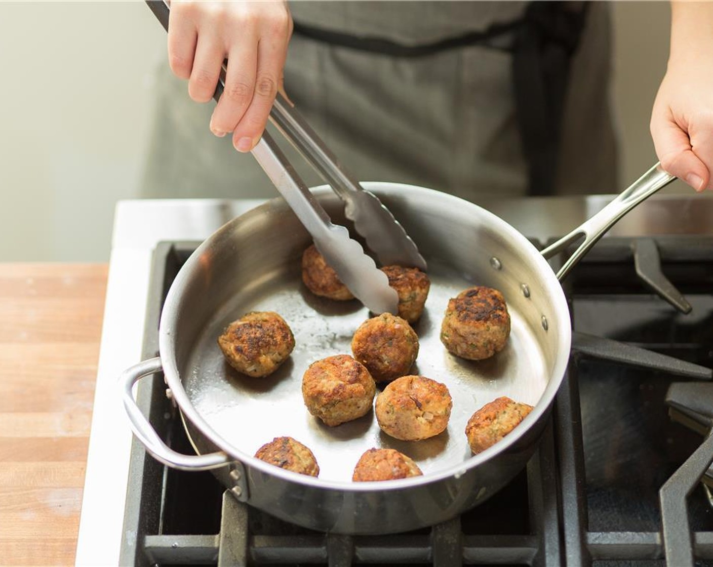 step 5 Heat a large deep saute pan over medium high heat and add Olive Oil (1 Tbsp). Once hot, carefully add the meatballs and brown on all sides. Transfer meatballs to a plate but do not remove pan from heat.