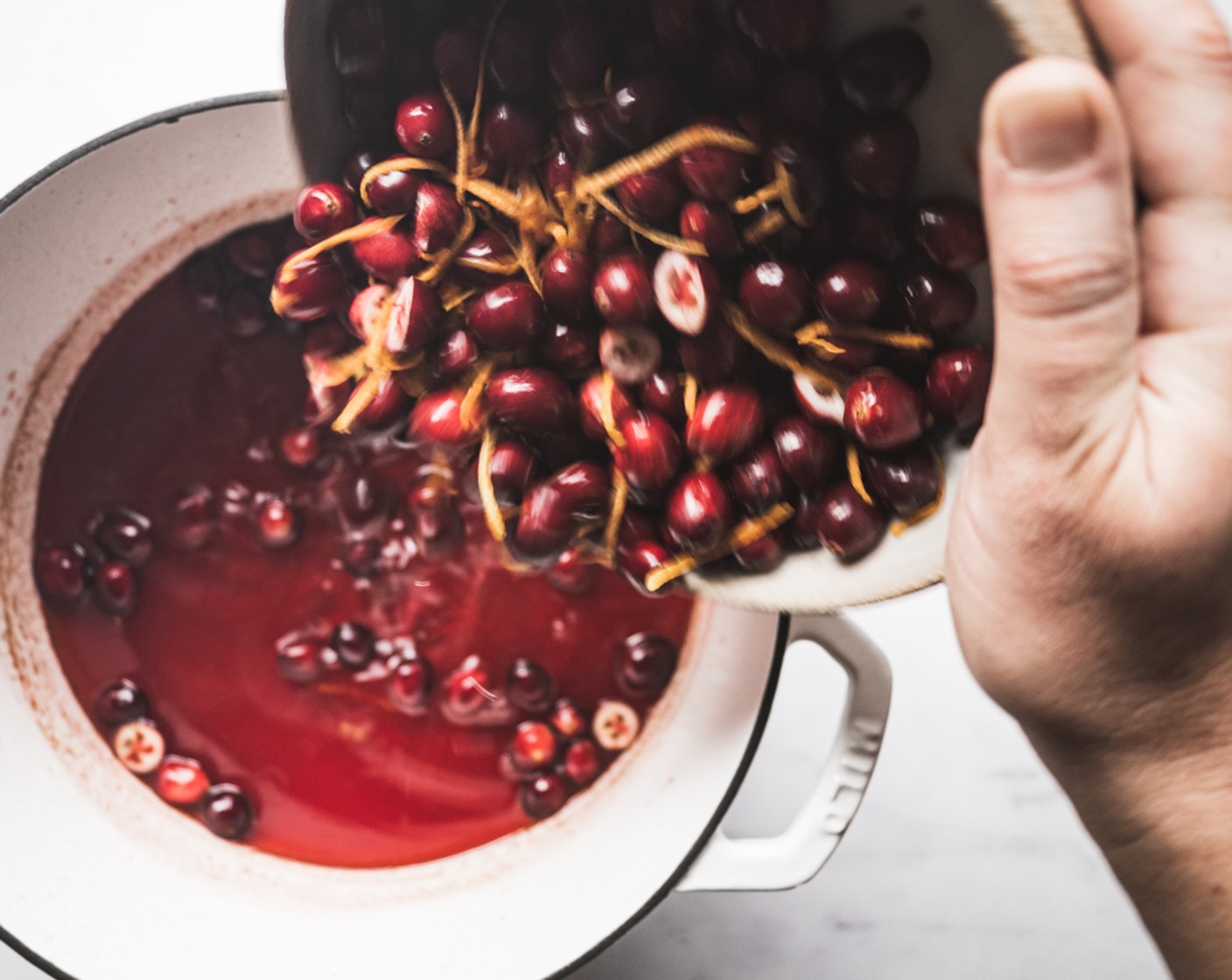 step 6 Once the sugar and liquid mixture has boiled for several minutes, turn off the heat and add in the prepared cranberries and orange zest. Stir to coat the cranberries and immediately cover with a lid to trap the heat.