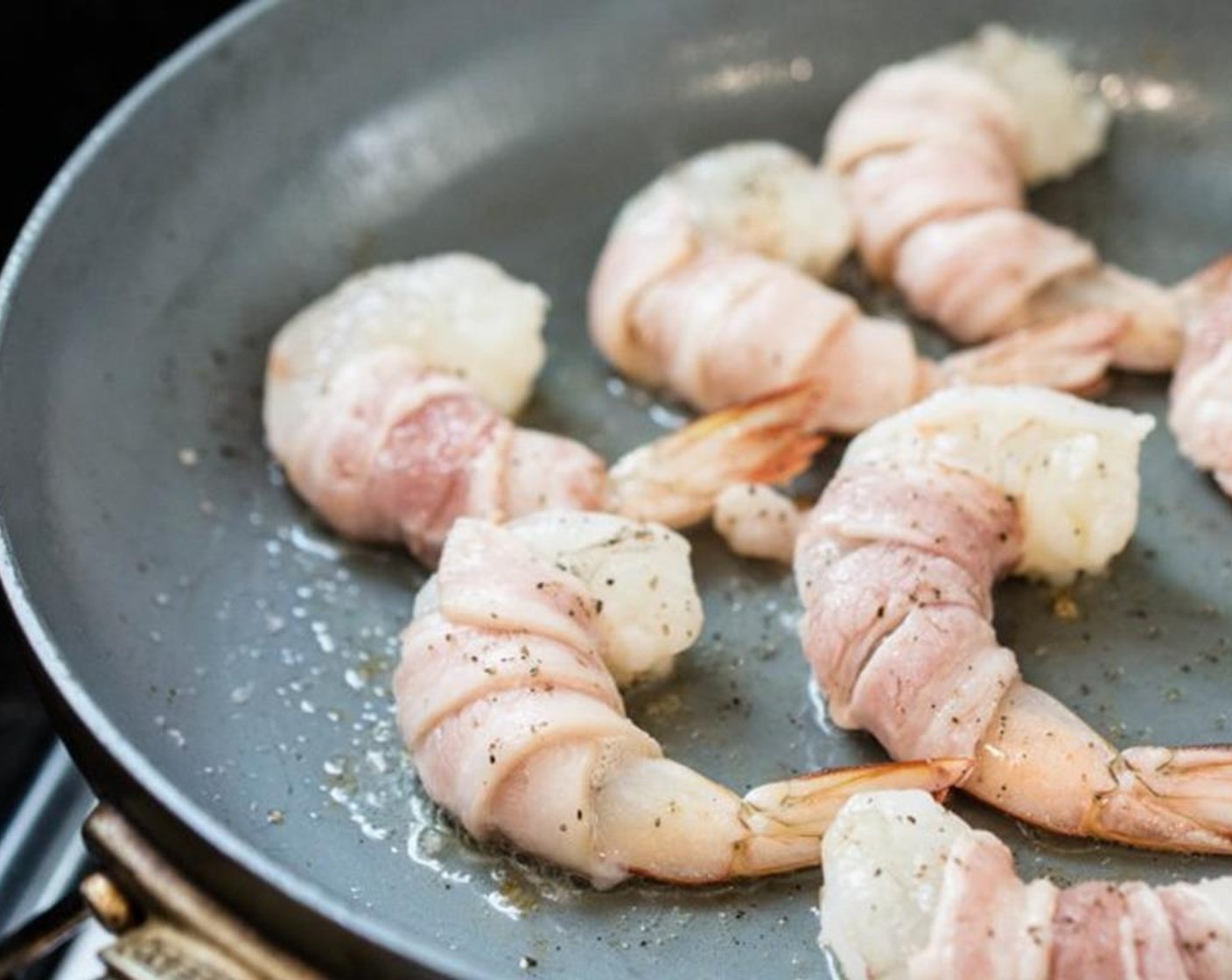 step 2 Heat up Cooking Oil (2 Tbsp) in a large shallow frying pan over medium-high heat. Place the bacon wrapped shrimp on to the pan. Don't move them! Let them sit for a minute, then use a pair of tongs to flip them over to cook the other side for another minute.
