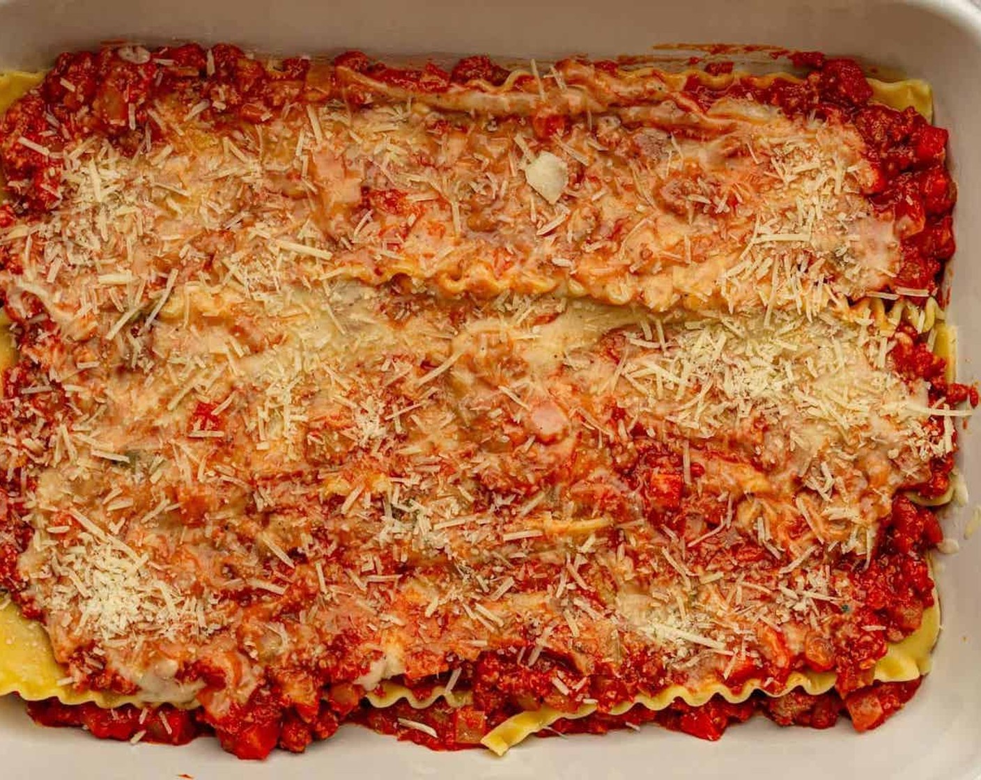 step 12 Add a layer of lasagna noodles. Spread a layer of the bolognese over the layer of noodles, then add a layer of béchamel (approximately 1/3 cup). Sprinkle about 2 Tbsp of Parmesan Cheese (1/2 cup) on top.