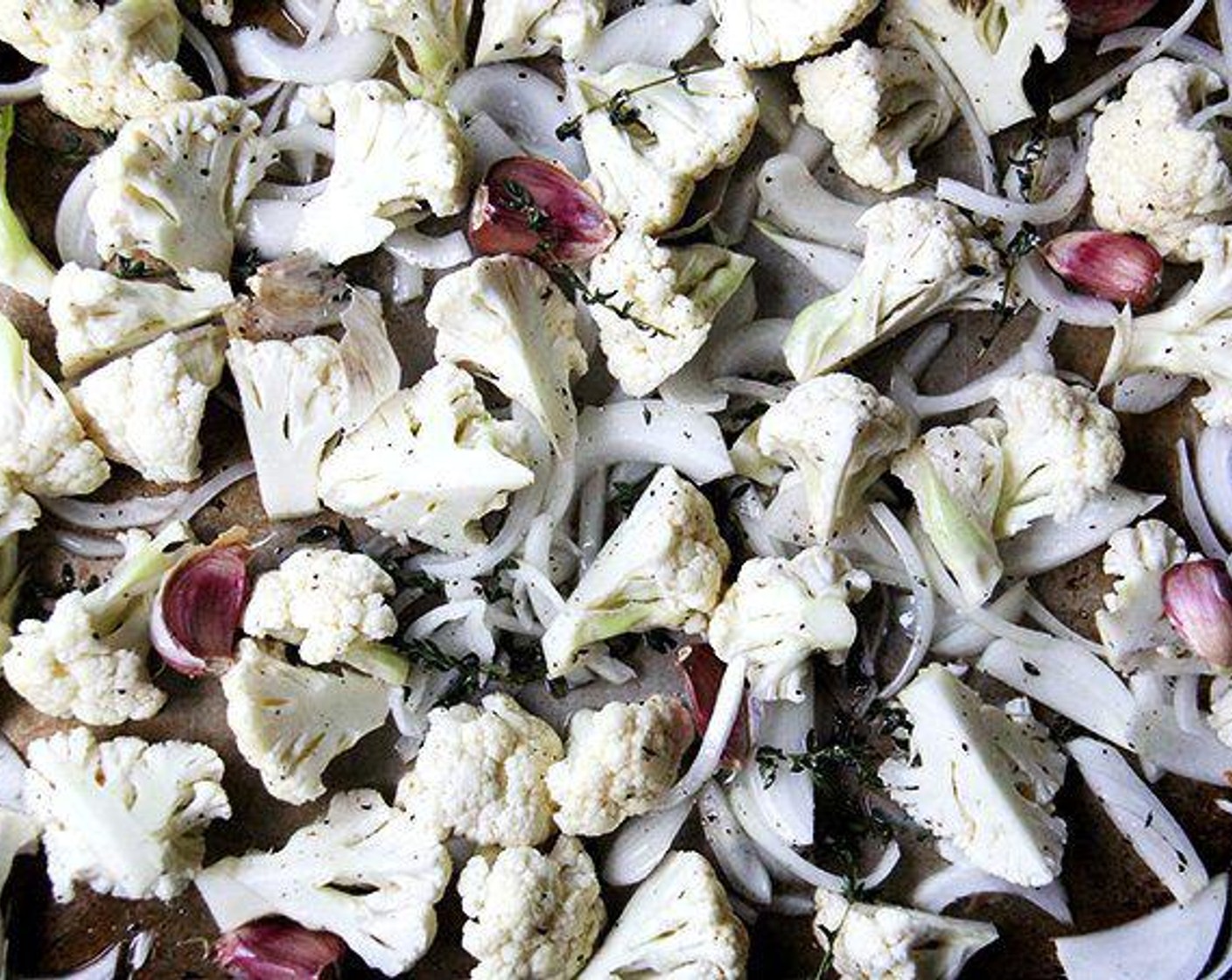 step 2 Toss Cauliflower (1 head) on a large rimmed baking sheet with Onion (1), Fresh Thyme (4 sprigs), Garlic (4 cloves), and Olive Oil (3 Tbsp). Season with Kosher Salt (to taste) and Ground Black Pepper (to taste).