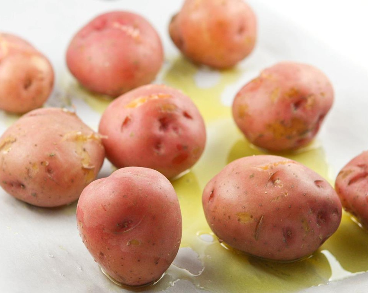 step 3 Preheat the oven to 350 degrees F (180 degrees C). Place parchment paper on a rimmed baking sheet and drizzle with Olive Oil (as needed). Remove the potatoes from the pan of water and place them on parchment paper. Smash each potato with a fork a couple of times.