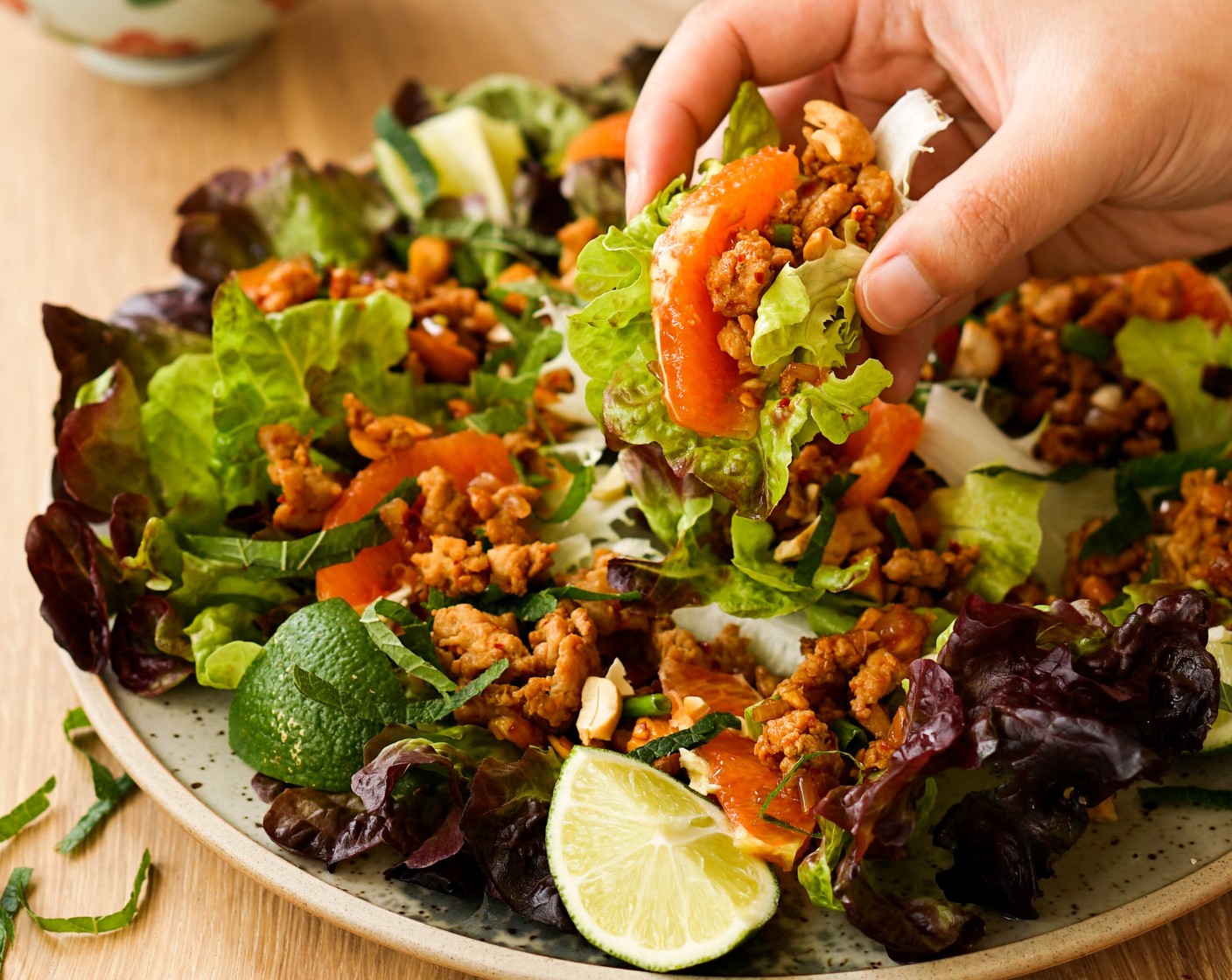 step 4 Arrange a bunch of Lettuce Leaves (as needed) on a serving platter. Fill each lettuce leaf with a heaping spoonful of larb and a small wedge of the Orange (1). Garnish with Fresh Mint (1 handful) and enjoy with extra limes!
