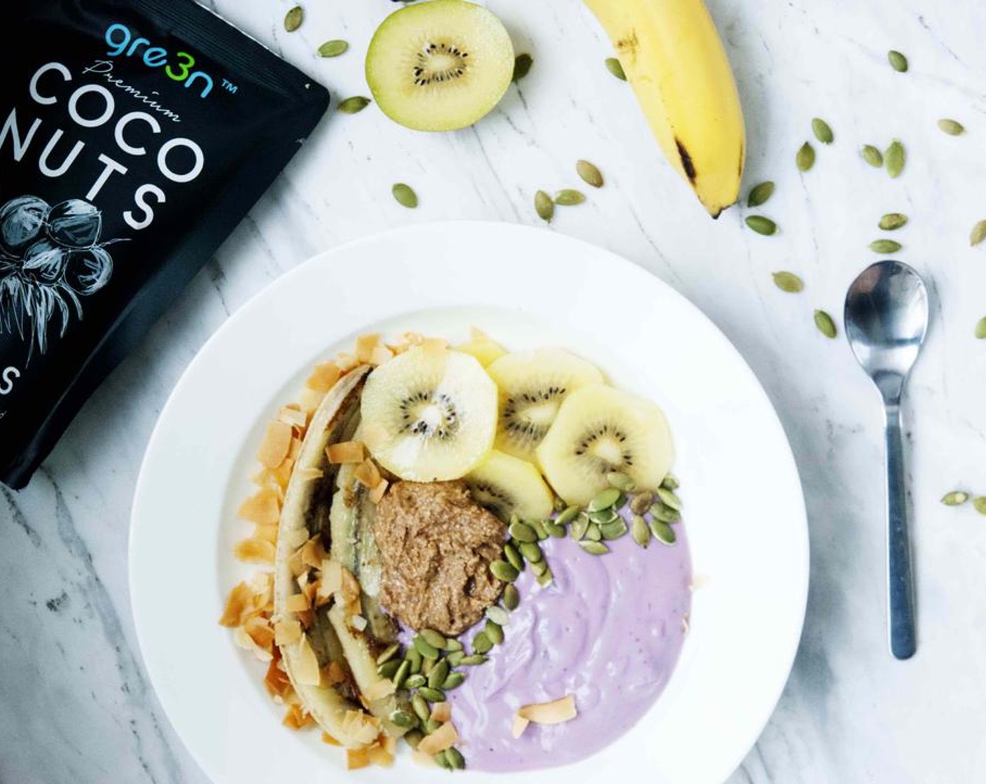 step 2 To assemble your bowl, just scoop out Blueberry Yogurt (1/2 cup) and Natural Almond Butter (2 Tbsp), lay the banana on the side, slice up the Kiwifruit (1/2) and add that too and finish it off by sprinkling Pepitas (1 tsp) and Coconut Chips (1 Tbsp) on top.