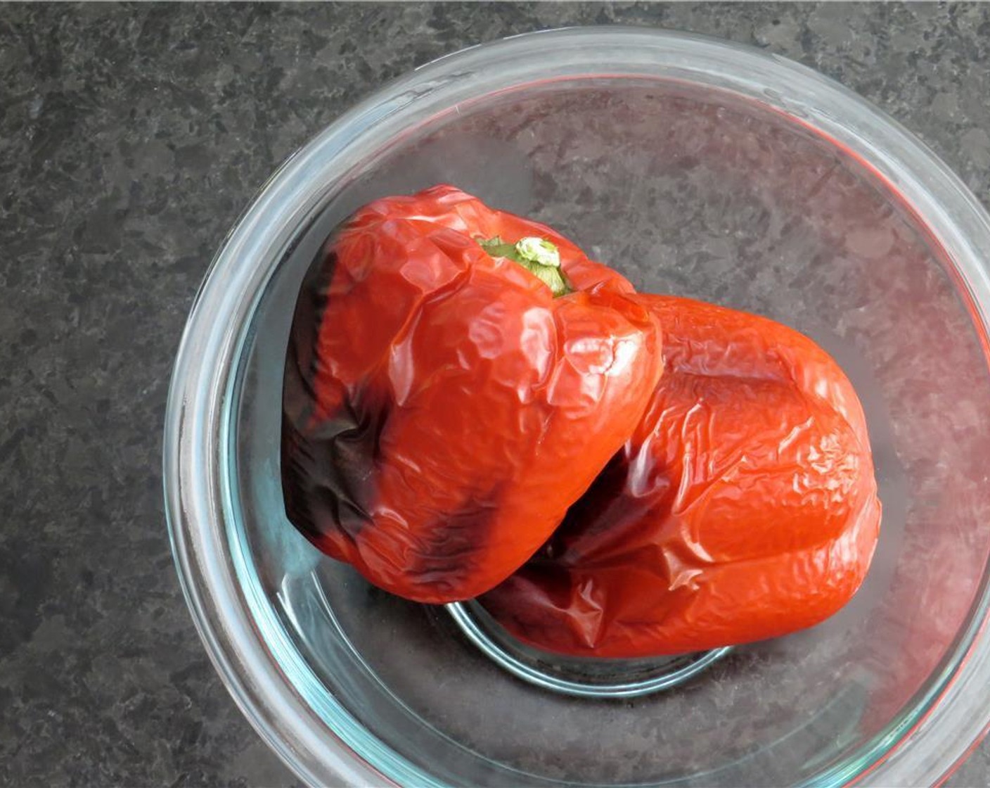 step 2 Place Red Bell Peppers (2) on a baking sheet, and roast for 30 minutes, until flesh is softened and skin is blackened. Remove red bell peppers from the oven, and place them in a small glass bowl. Cover the bowl with cellophane.