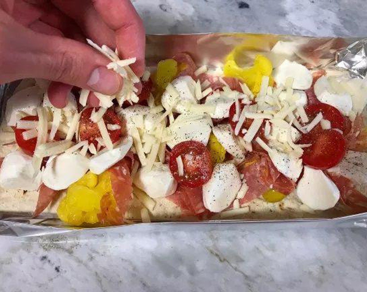 step 5 Start off by spreading out the pickled vegetables on the flatbread. Next, layer with the deli meats and fresh mozzarella slices. Then, top with cherry tomatoes and lightly Ground Black Pepper (to taste) the tomatoes. Finish toppings by sprinkling the Parmesan Cheese (1/4 cup) on top.