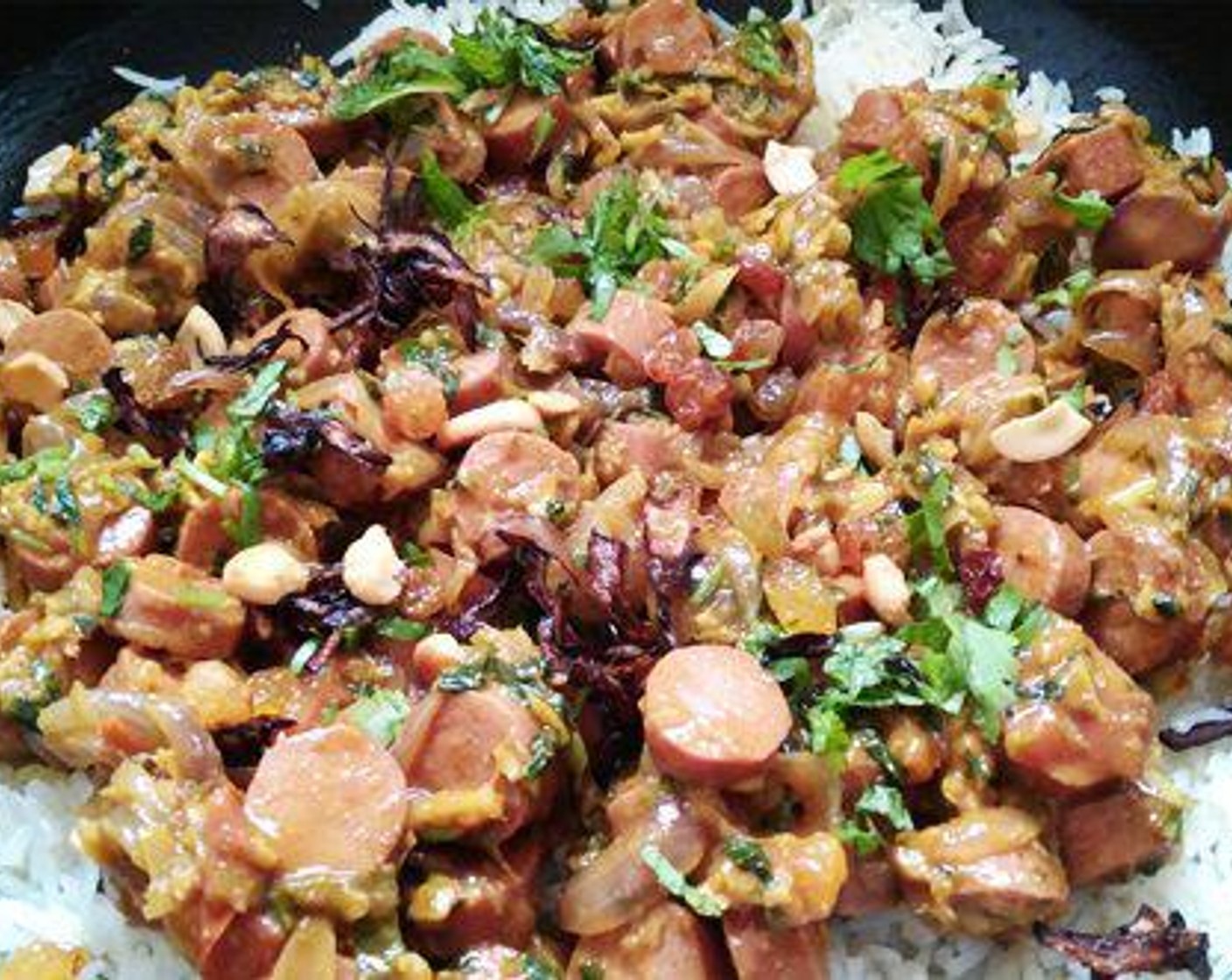 step 11 Take half of the cooked rice and keep aside. To the rest of the rice, add the sausage masala, fried onion, cashew nuts, raisins, and a little cilantro and mint leaves.