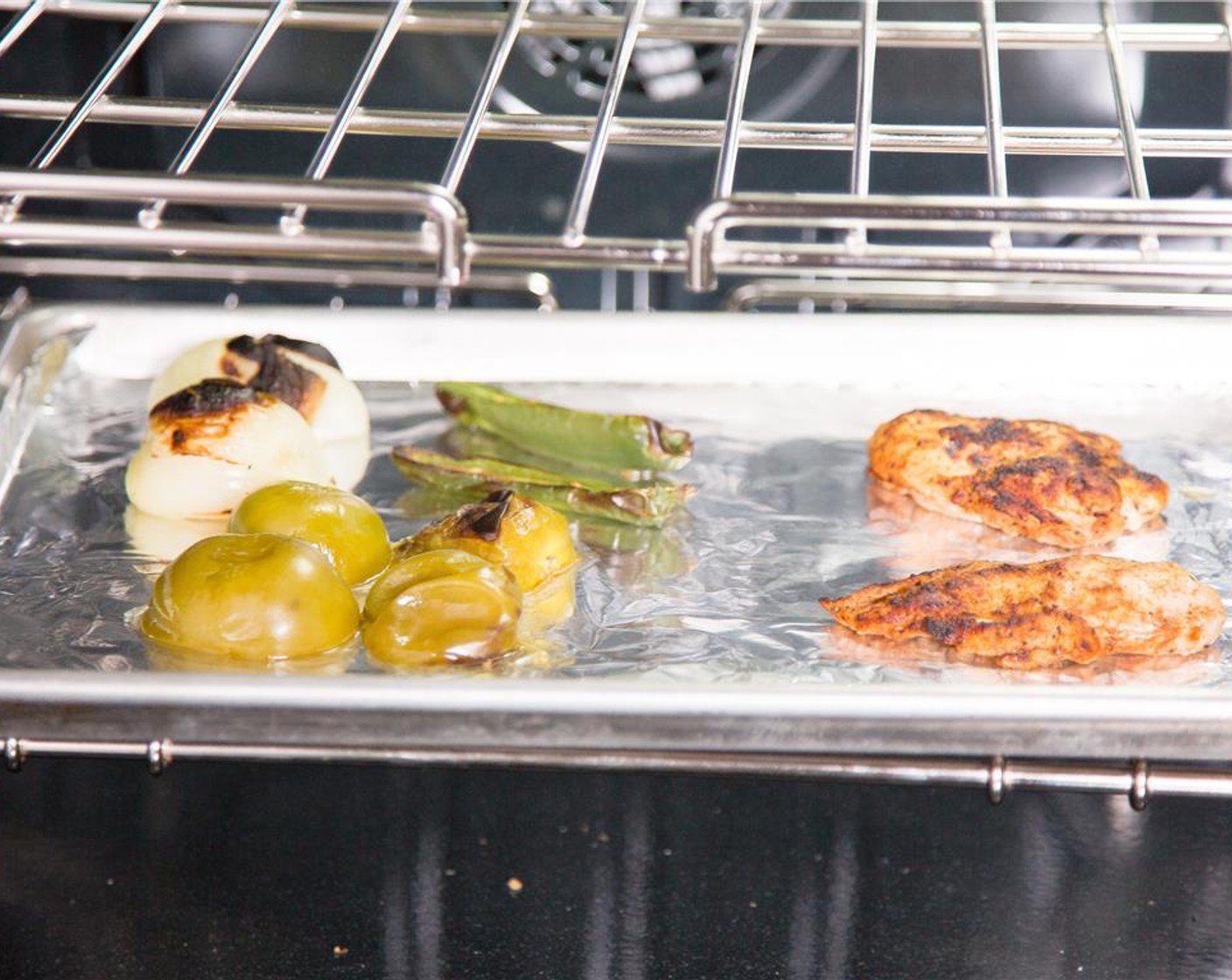 step 10 Place the chicken breasts side by side on the opposite side of the sheet pan from the tomatillos, jalapeno, and onion. Place the sheet pan under the broiler and allow to cook for nine minutes until the chicken is cooked through and the jalapeno and tomatillo are charred.