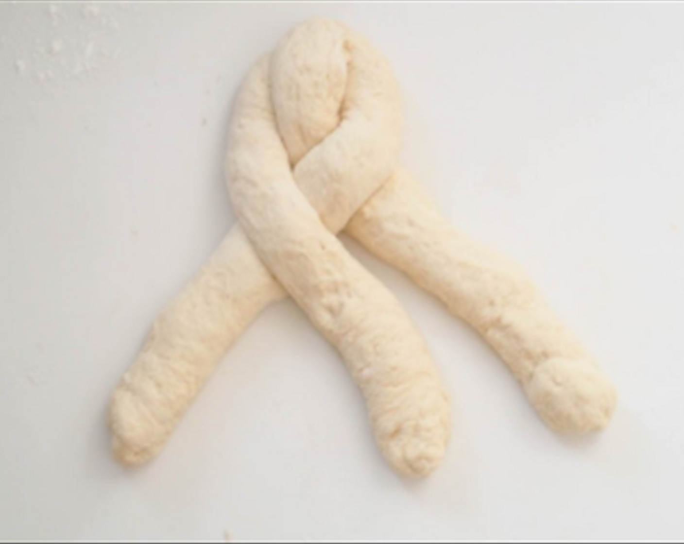 step 5 Punch down the dough to release the air. Transfer the dough to a clean floured surface then divide into 3 equal portions. Form each dough into a strand (about 12 inch long) and braid them together. Place the braided dough in the prepared baking pan.