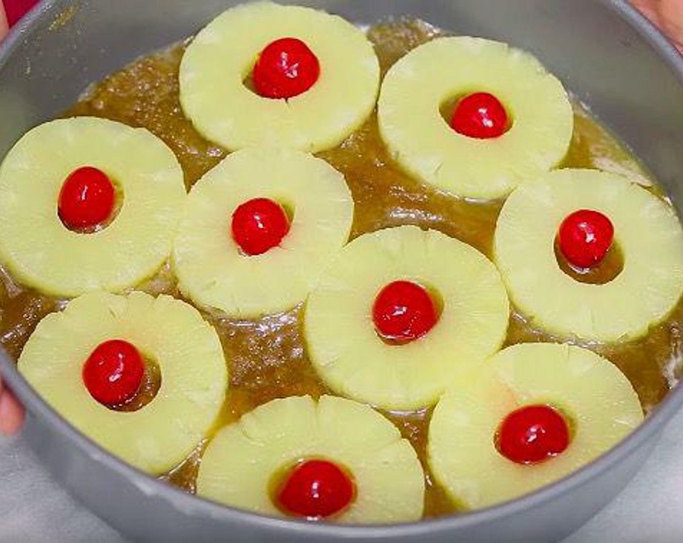 step 2 Place Butter (1/4 cup) into a 9 inch (deep dish) round cake pan. Make sure it is a deep pan. Sprinkle with Brown Sugar (1/2 cup). Top with Canned Pineapple Slices in Juice (8 slices) and arrange Maraschino Cherries (8) inside the pineapple hole. Set aside.