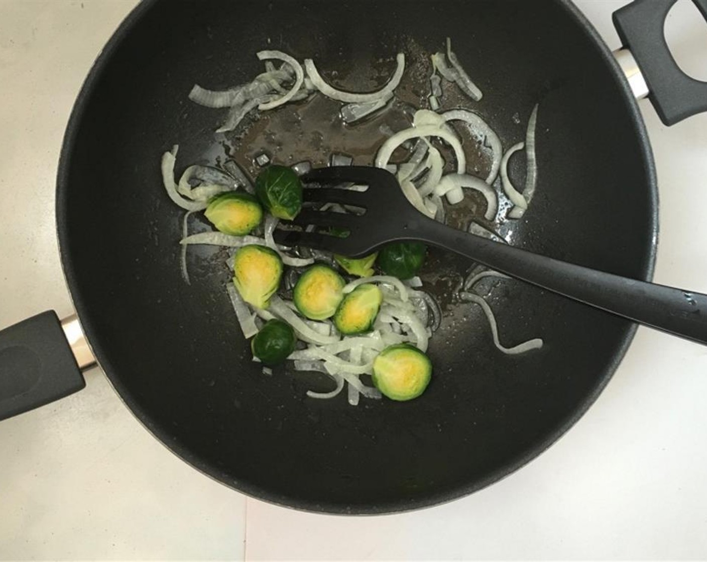 step 1 Pour the Vegetable Oil (2 Tbsp) in a large non-stick pan or wok and place it over medium-high heat. Then add the Brussels Sprouts (6) together with the Garlic (1 clove) and Onion (1/2). Gently fry the vegetables for 4 minutes.