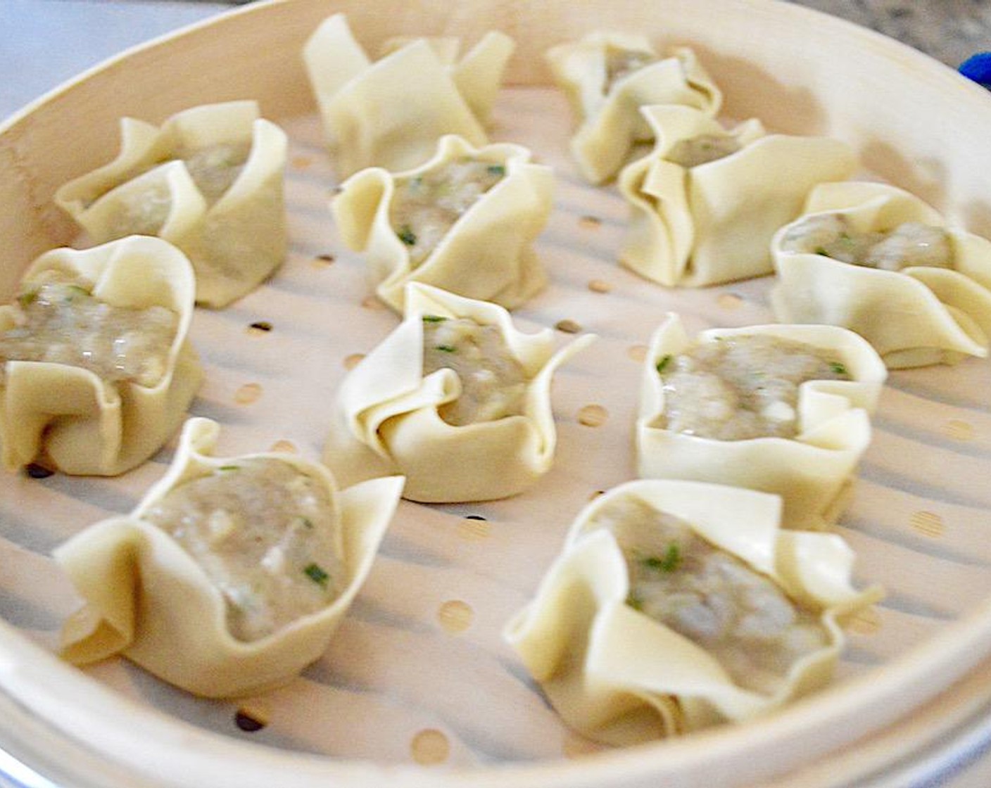 step 4 Line each tier of the bamboo steamer with parchment paper, then fill each tier with 12 of the shu mai. Close the steamer and place it over the simmering water. Let the shu mai steam for about 8 minutes, until the filling is opaque and cooked through.