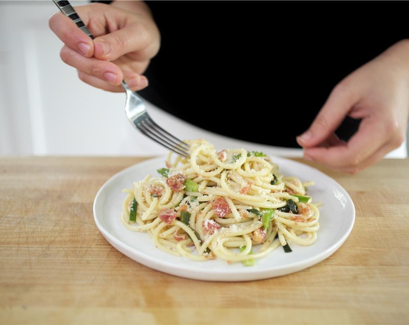 step 12 Place the Bucatini into the center of two plates, displaying as much green onions and pancetta on top as possible. Top with remaining Parmesan Cheese (1 Tbsp).