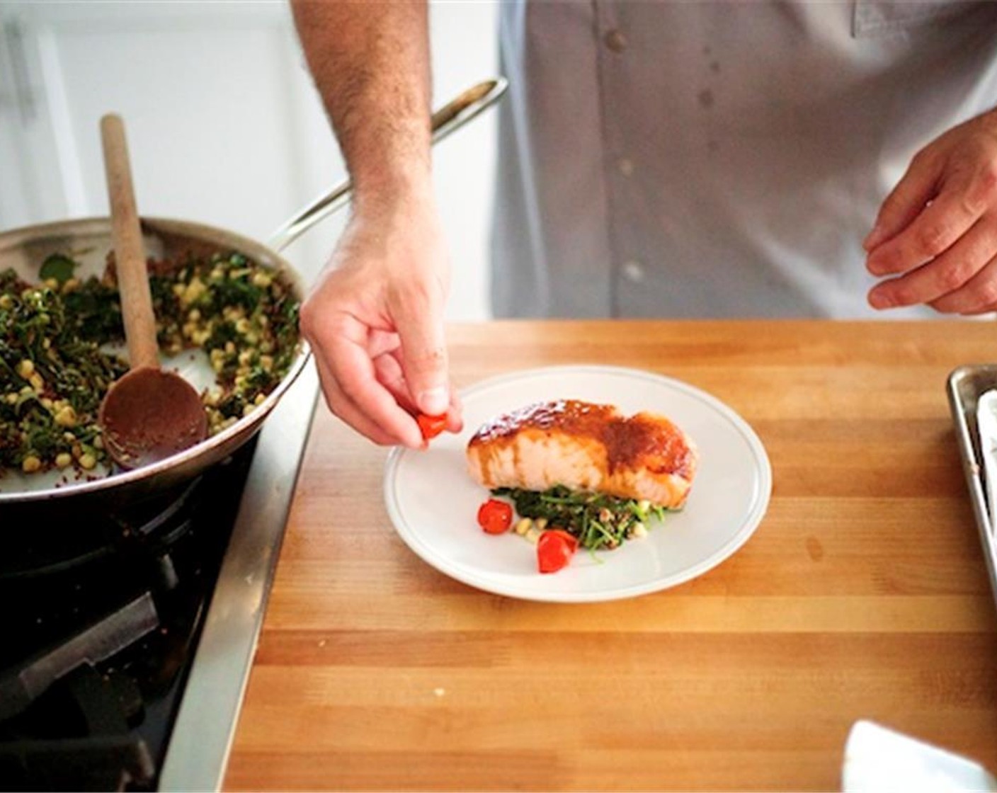 step 18 Divide the corn quinoa blend in two and place in the center of two plates. Lay salmon over the corn quinoa blend. Evenly separate the roasted tomatoes and place around the salmon on the inside rim of each plate.