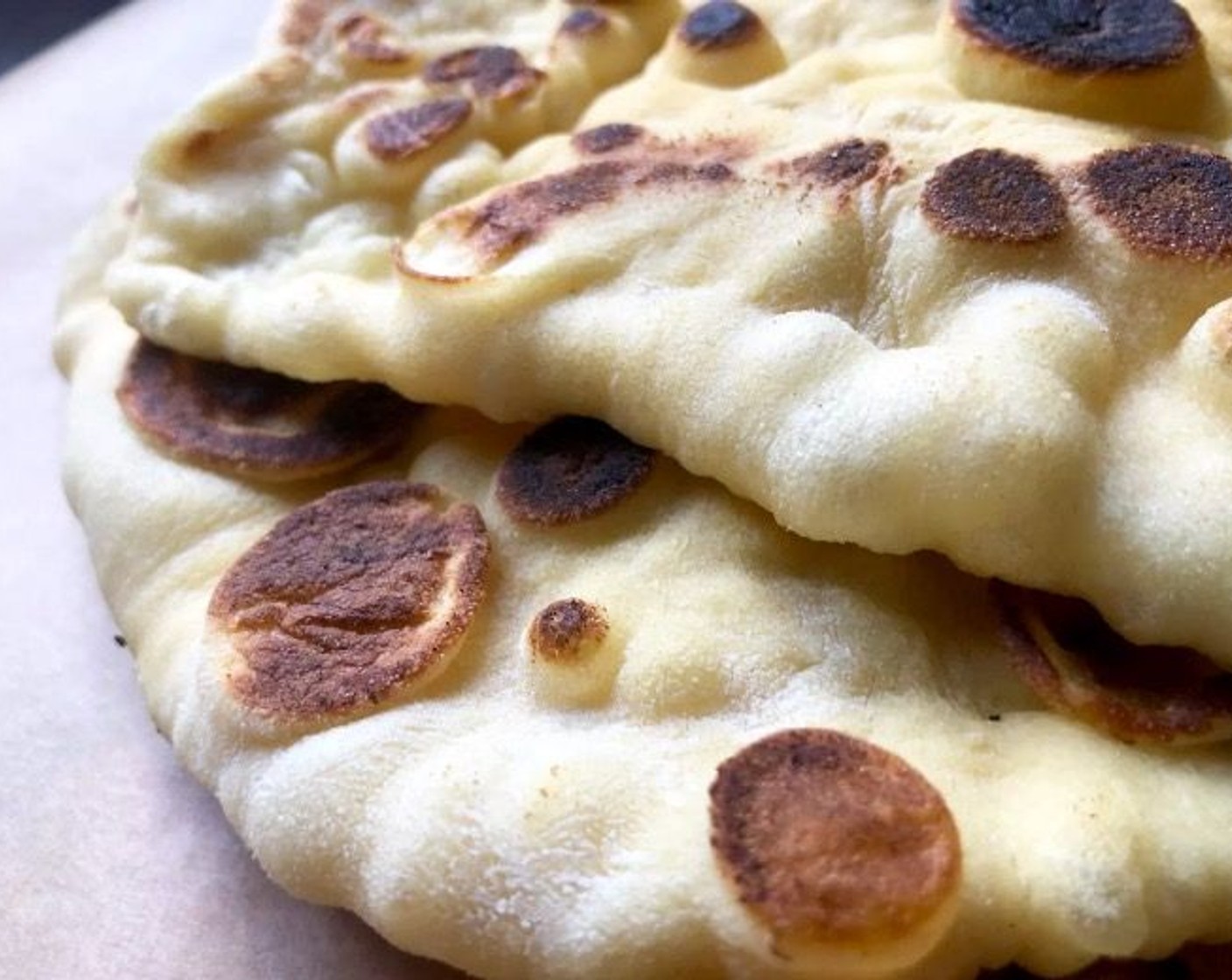 step 11 Flip the naan and cook uncovered for another minute or so until multiple toasted spots appear on the underside. As you work, keep the stack of cooked naan wrapped in a linen towel.