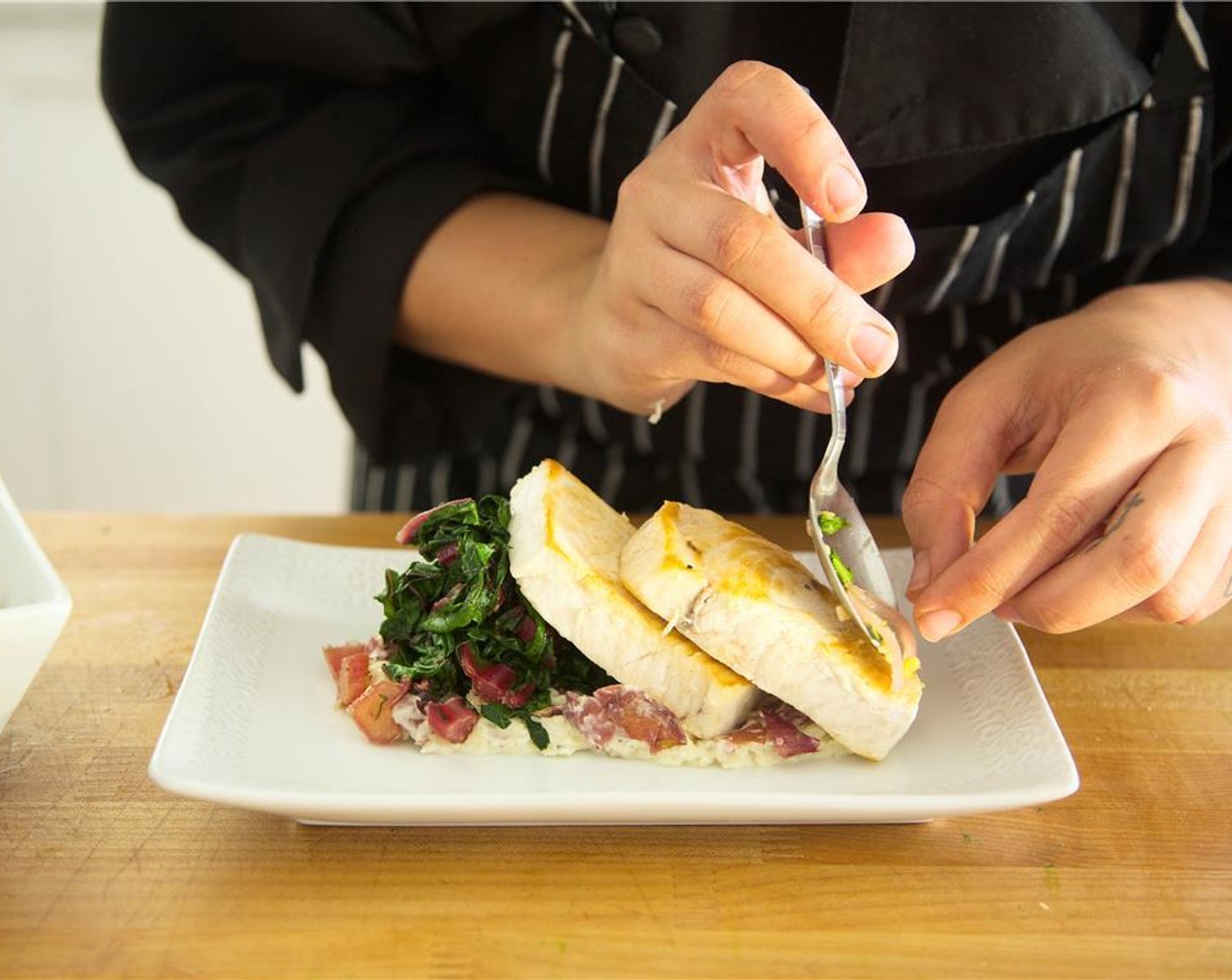 step 20 Place a portion of smashed potatoes on center of two plates in a line. Plate swiss chard at one end of the potatoes with height. Lay the swordfish stacked together, leaning against one another. Drizzle sauce over the swordfish.