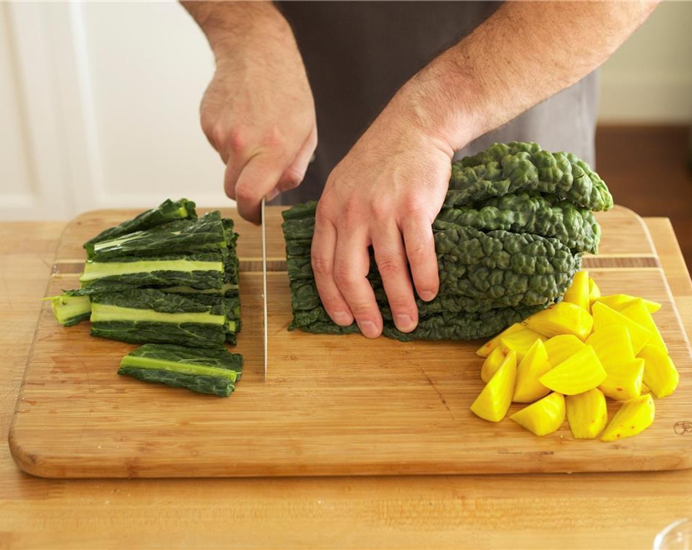 step 3 Trim two inches off bottom of Tuscan Kale (2 bunches) and discard bottoms. Place one and a half bunches of kale leaves on one sheet pan with top face of leaf facing up. Place remainder of kale on other half of second sheet pan next to beets.