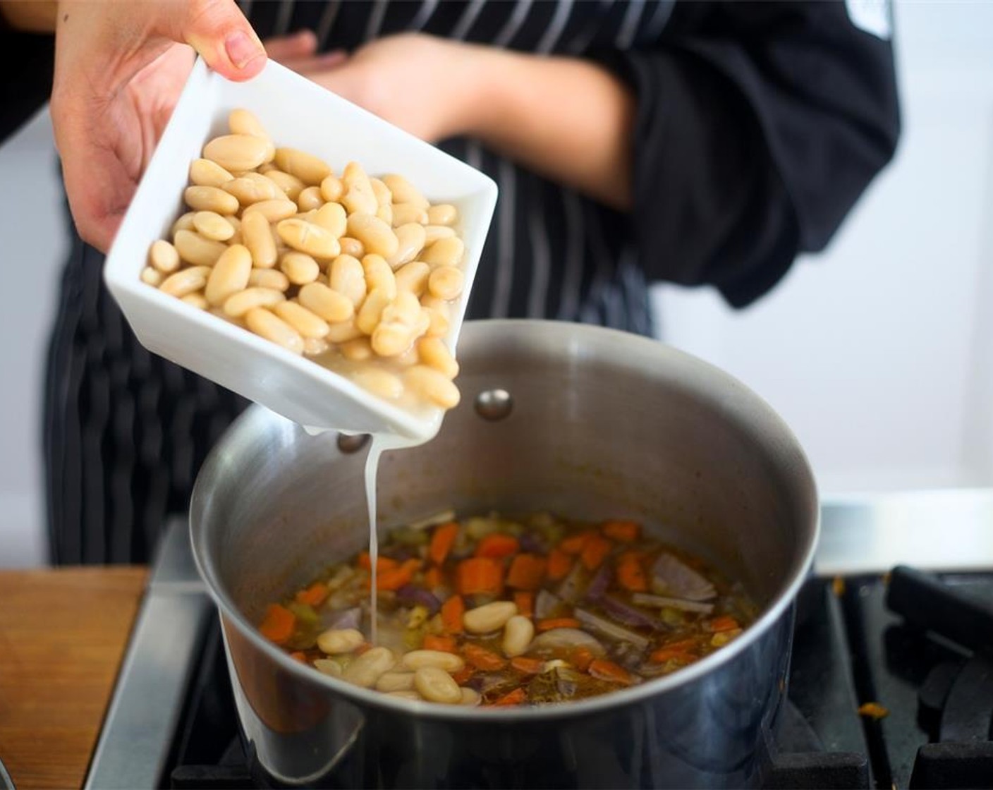 step 11 Add Canned Cannellini White Kidney Beans (2 cups) along with their juices and vegetable broth. Bring to a boil. Then, reduce heat to medium low and simmer for 15 minutes. Then, reduce heat to low.
