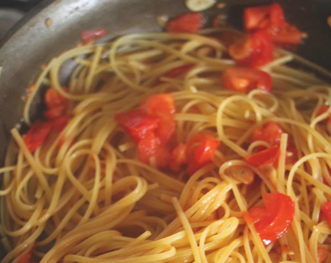 step 6 Your pasta should be about halfway cooked.  Turn the pan to high heat and add the pasta right from the pot. Don't drain the pasta first.  You'll continue to cook it in the garlic, oil, and tomatoes until it is al dente.