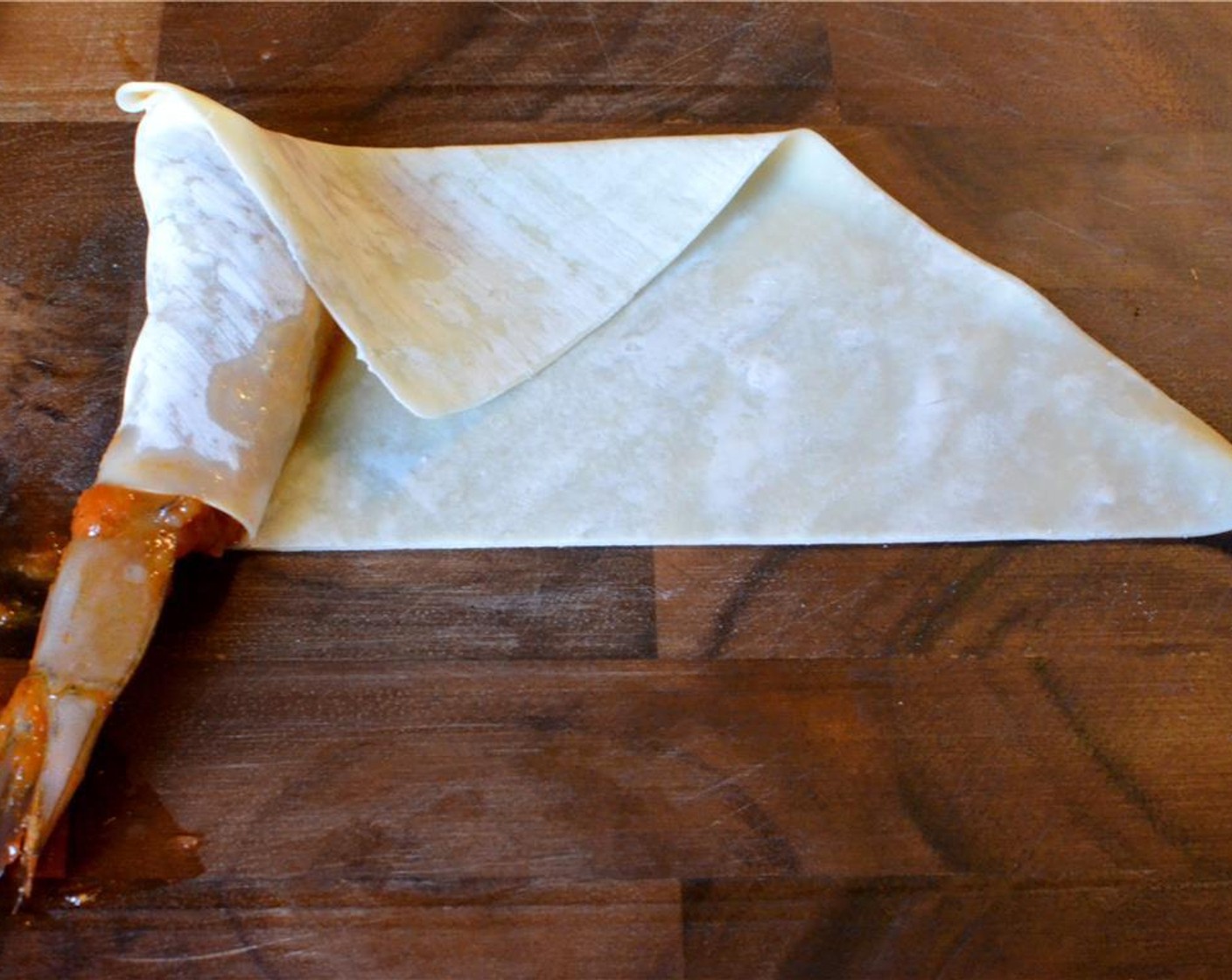 step 10 Then fold the top corner down, making sure to cover the top end of the shrimp. Roll the shrimp as tightly as possible and as straight as you can manage until there's just a little corner left.
