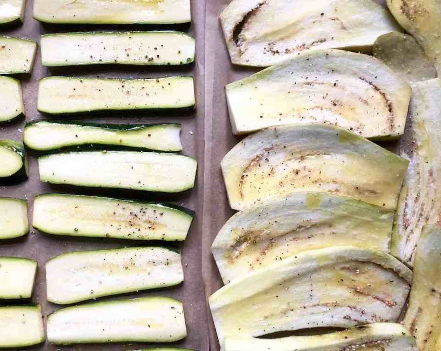 step 5 Arrange the Eggplants (2) and Zucchini (3) on large rimmed sheet pans lined with parchment paper. Brush generously with little oil and sprinkle lightly with Salt (to taste) and Freshly Ground Black Pepper (to taste).