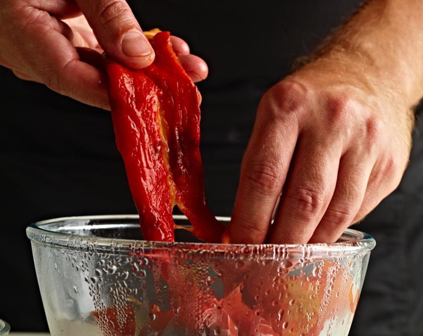 step 3 Roast the Red Bell Pepper (1) over a hot grill until the skin starts to blacken. Place in a bowl and cover well with cling-film. When cool, peel the skin off the peppers by hand, cut them in half and remove the seeds. Set aside.