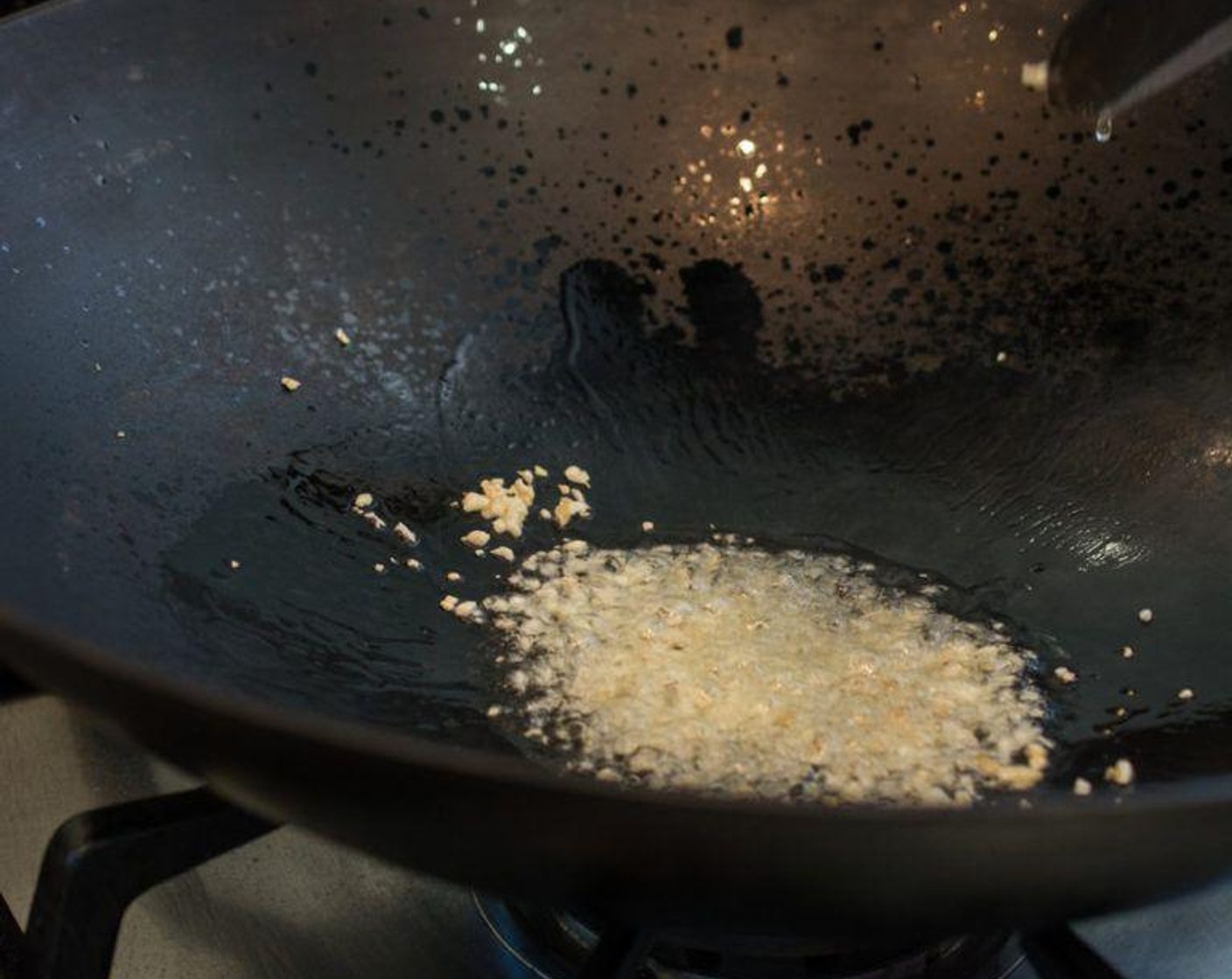 step 2 Heat up your wok over maximum heat. As soon as it starts to smoke a little, pour the Cooking Oil (3 Tbsp) into the wok, immediately followed by the Garlic (3 cloves). Give it a quick stir.