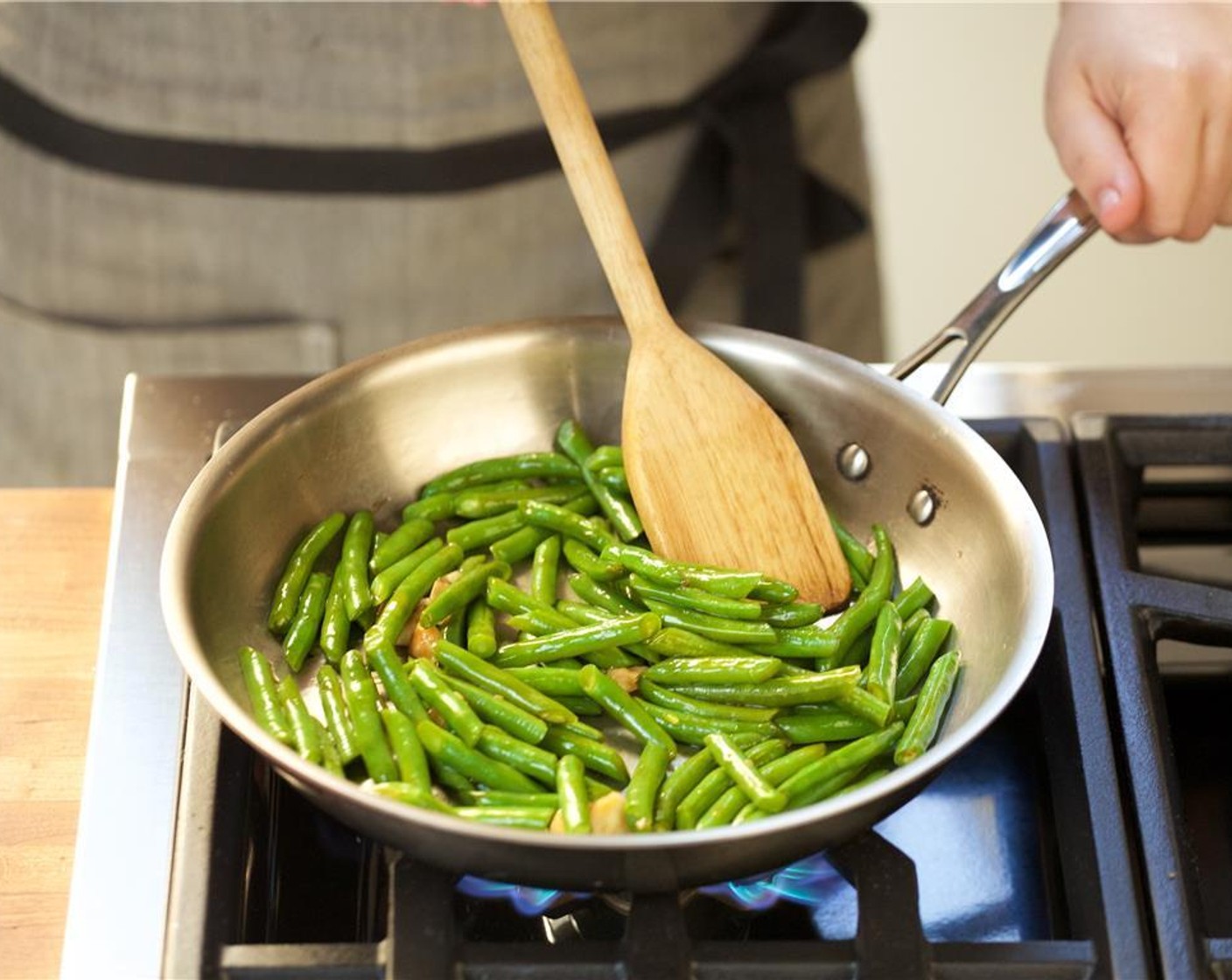 step 8 Heat a medium saute pan over high heat. When hot, add one tablespoon of canola oil. Add the garlic cloves and saute for ten seconds until aromatic. Add the green beans and cook for one minute.