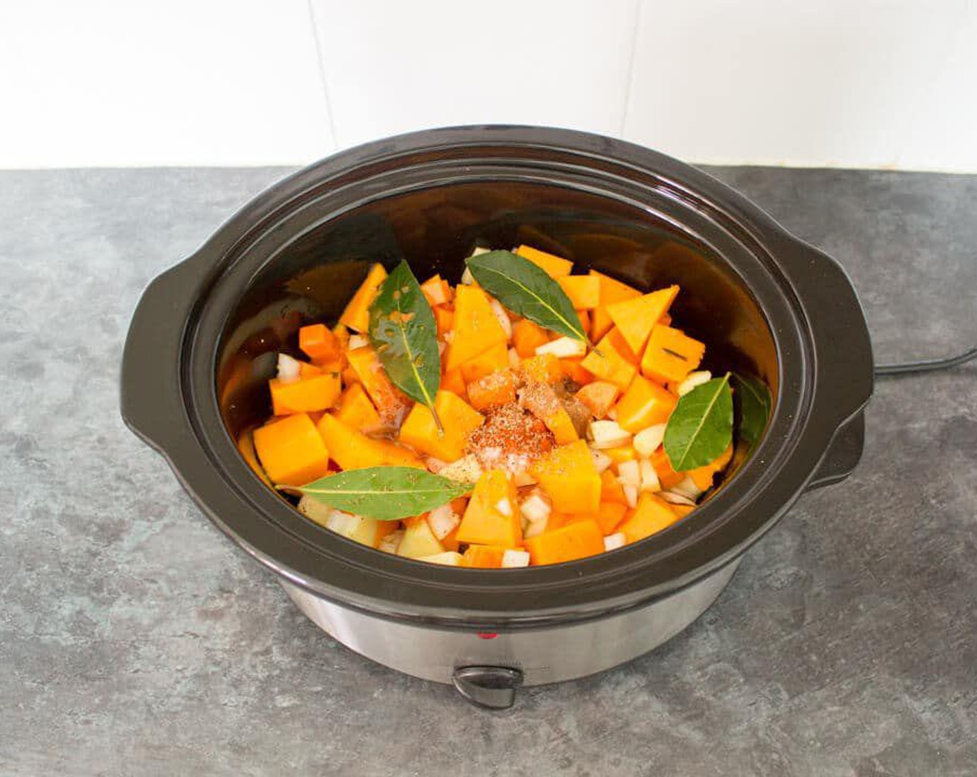 step 1 Add Butternut Squash (1), Carrot (1), Granny Smith Apple (1), Onion (1), Garlic (2 cloves) to the slow cooker, then add Vegetable Stock (2 cups), {@10:}, Ground Cinnamon (1/4 tsp), Bay Leaves (4), Ground Nutmeg (1/4 tsp), and Paprika (1/4 tsp) and give it a little mix.