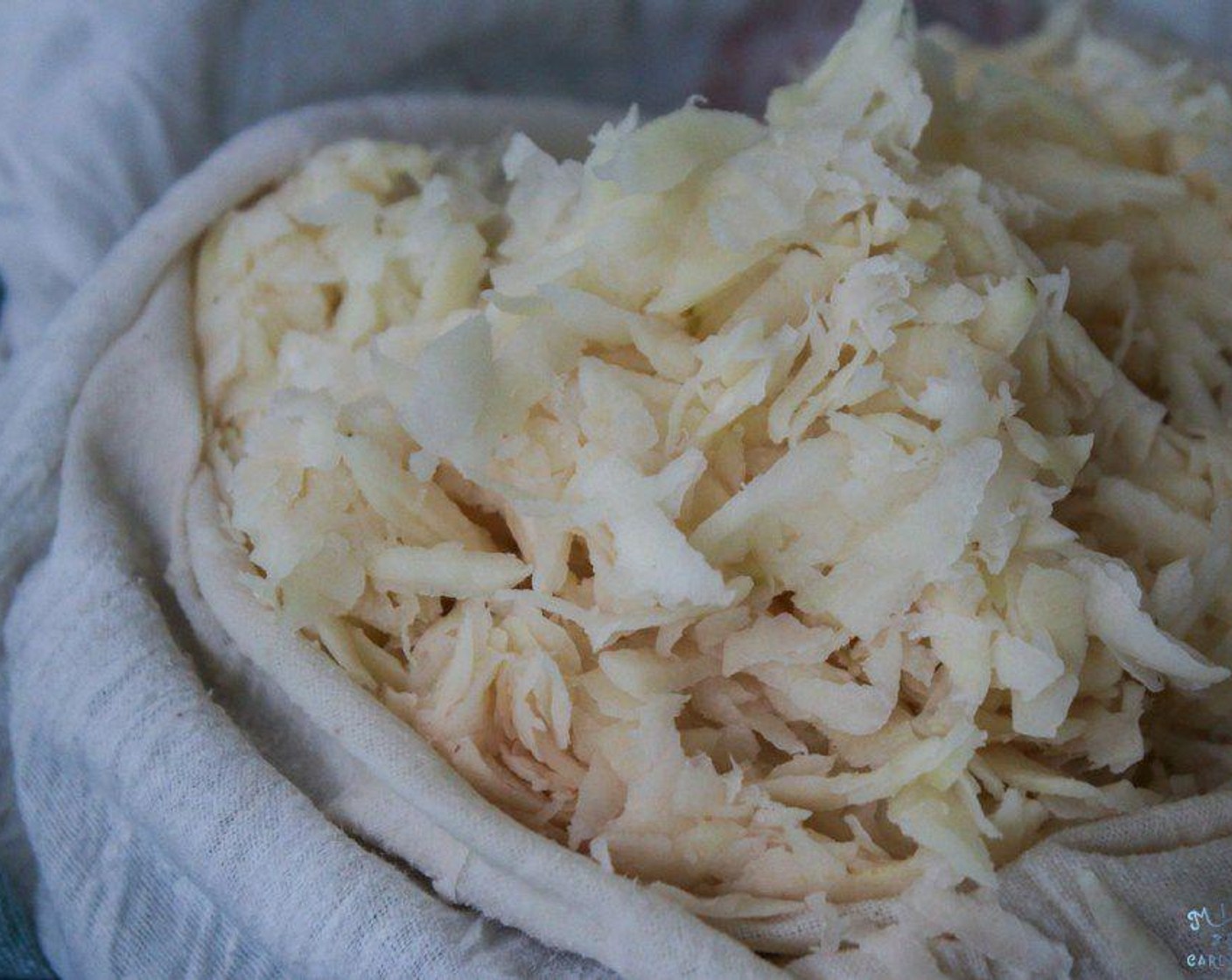 step 5 Line a bowl with a tea towel. Add grated potato and onion to the tea towel. Pick up the corners and twist the tea towel. Squeeze out as much liquid as you can from the potatoes and onions. Dump the potatoes and onions into a large bowl.