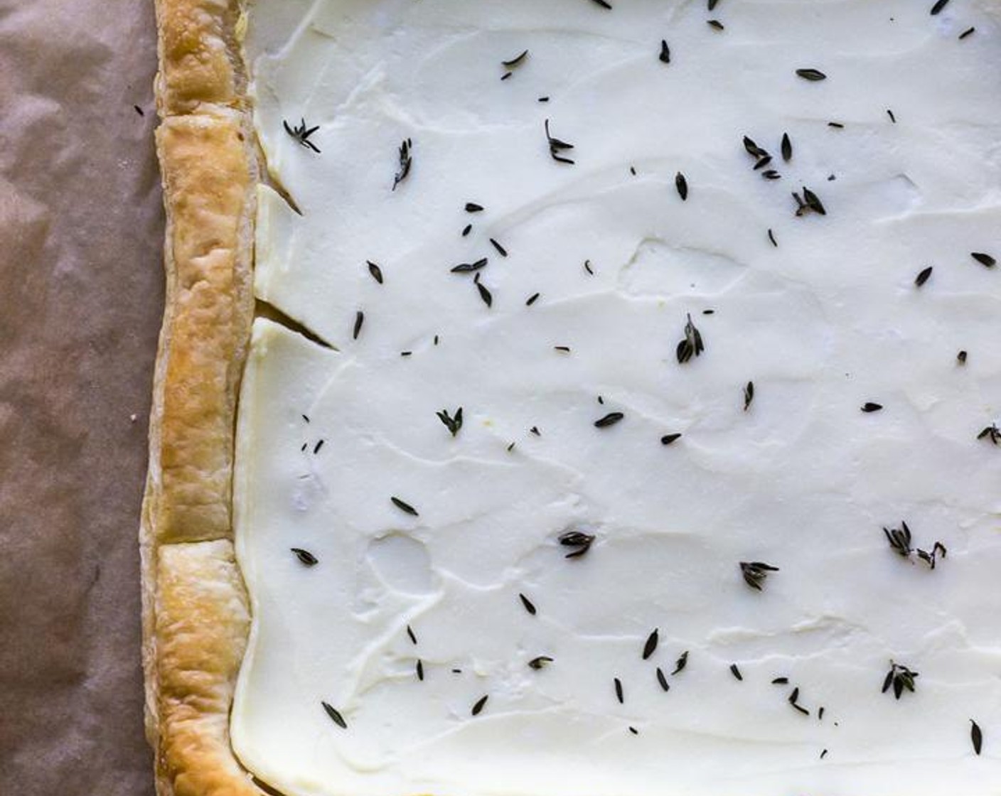 step 2 Place Puff Pastry (1) on a sheet of parchment paper and gently roll with a rolling pin to even out pastry. Place parchment with puff pastry on a baking sheet and evenly spread puff pastry with Ricotta Cheese (1/2 cup) leaving a 1 inch perimeter of puff pastry as you go.