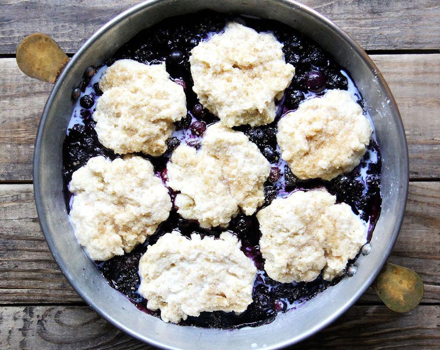 step 6 To assemble and bake the cobbler: Remove the berries from the oven; increase the oven temperature to 425 degrees F (220 degrees C). Drop the pieces of biscuit dough on the hot berry filling, spacing them about half inch apart. Brush biscuits with Milk (1/2 Tbsp) and sprinkle with Raw Cane Sugar (1/2 Tbsp).