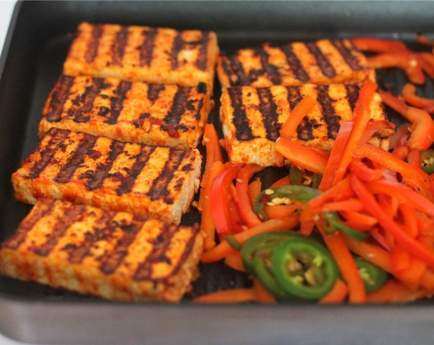 step 5 Bring a grill or frying pan to high heat, and cook the tofu well on each side. In the same pan, you can cook the pepper and jalapeno. Be sure not to discard the remaining sauce in the baking dish.